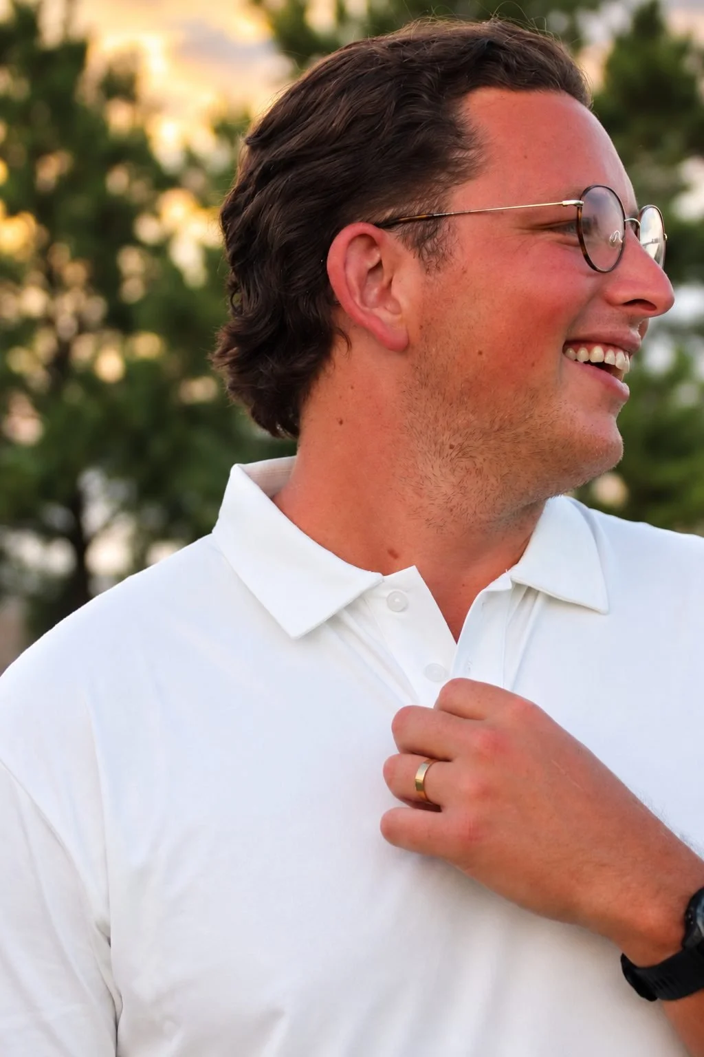Smiling man with glasses adjusting the collar of The Classic polo in white