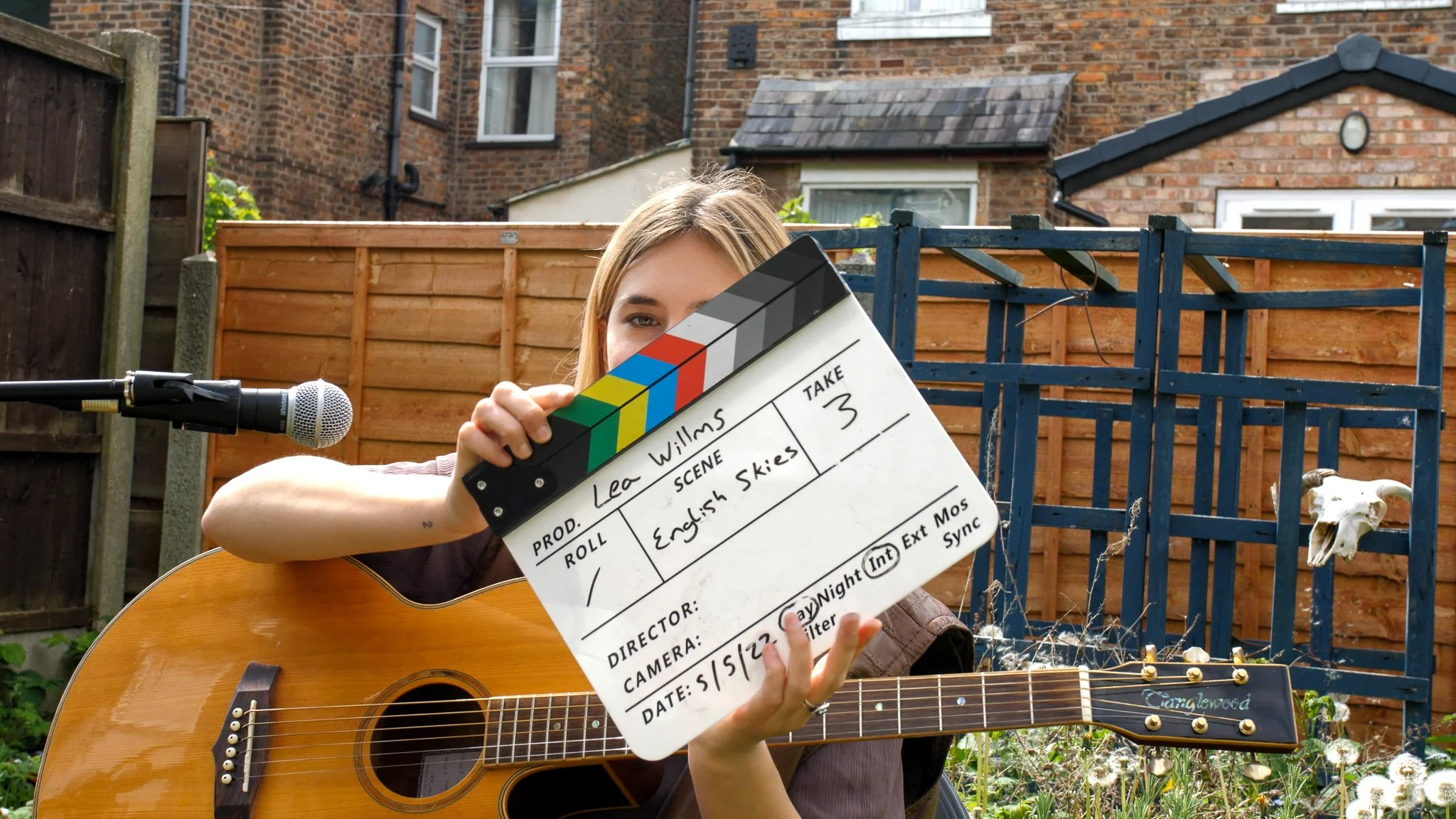 Behind-the-scenes footage of music video production featuring film slate and acoustic guitar.