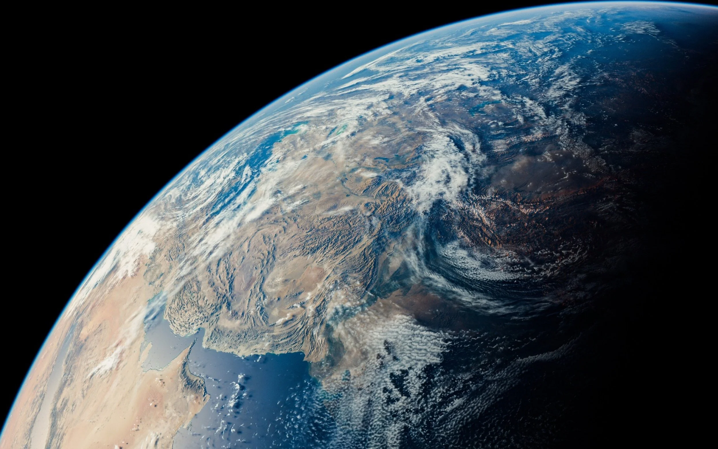 View of Earth from space showing parts of the Middle East, Asia, and surrounding oceans with cloud formations.