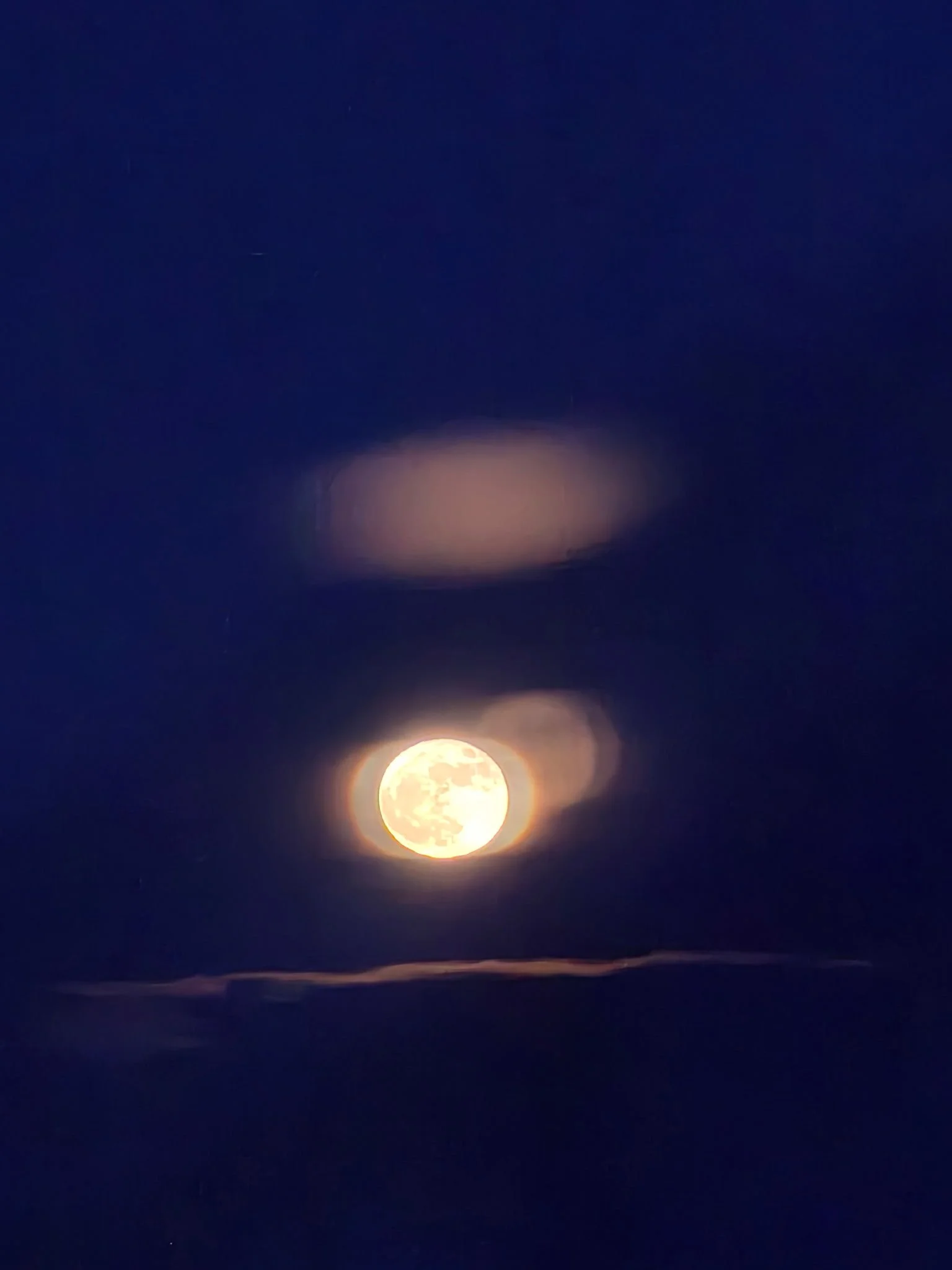 Full moon shining brightly in a clear night sky with some faint stars visible and a subtle glow on the horizon.