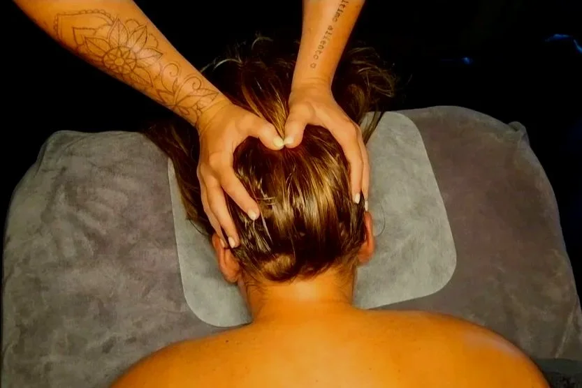 Person receiving a head massage while lying face down on a massage table.