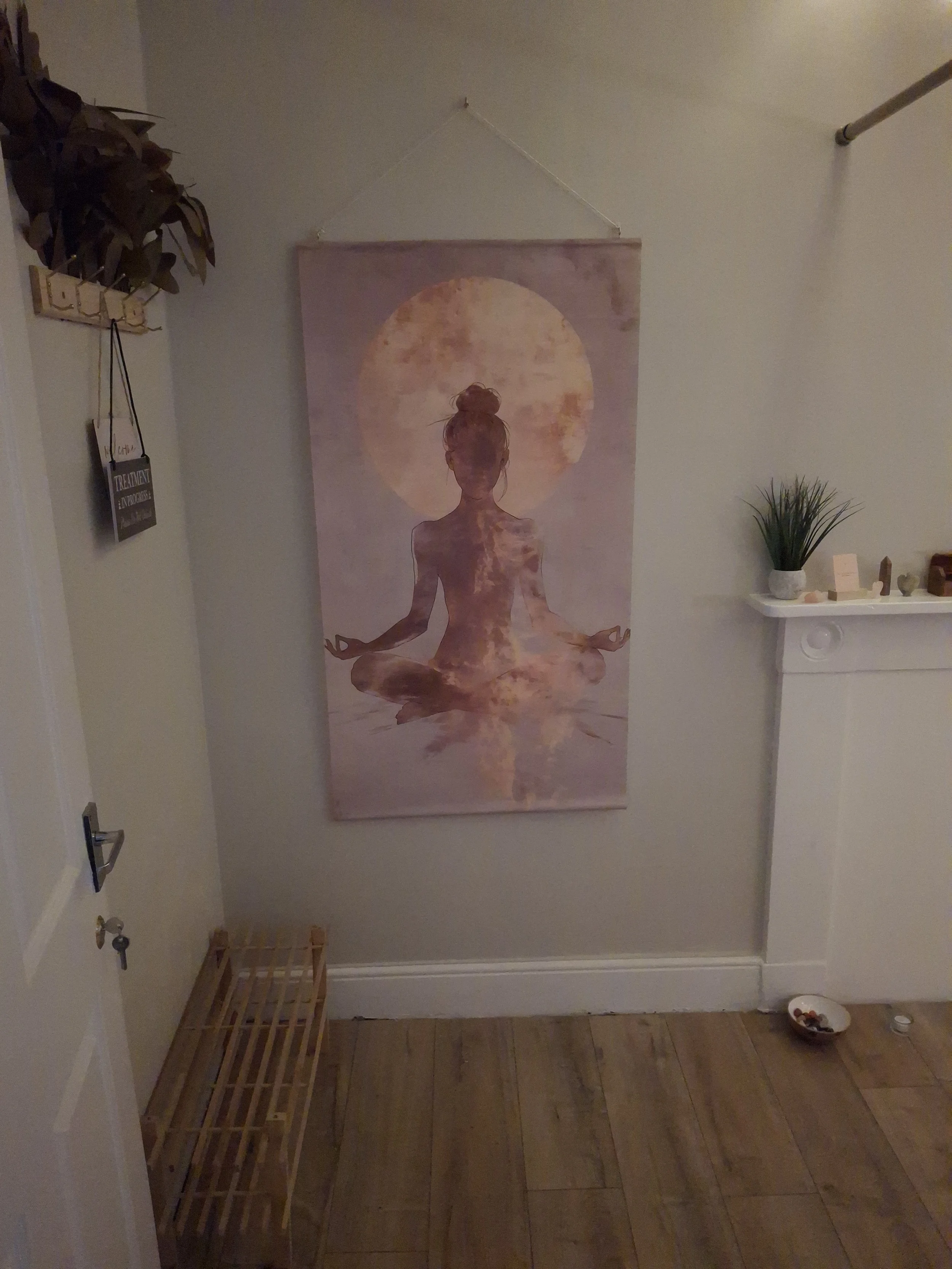 Wall hanging artwork depicting a woman in a meditative pose with a large sun or moon in the background, in soft pastel colors.