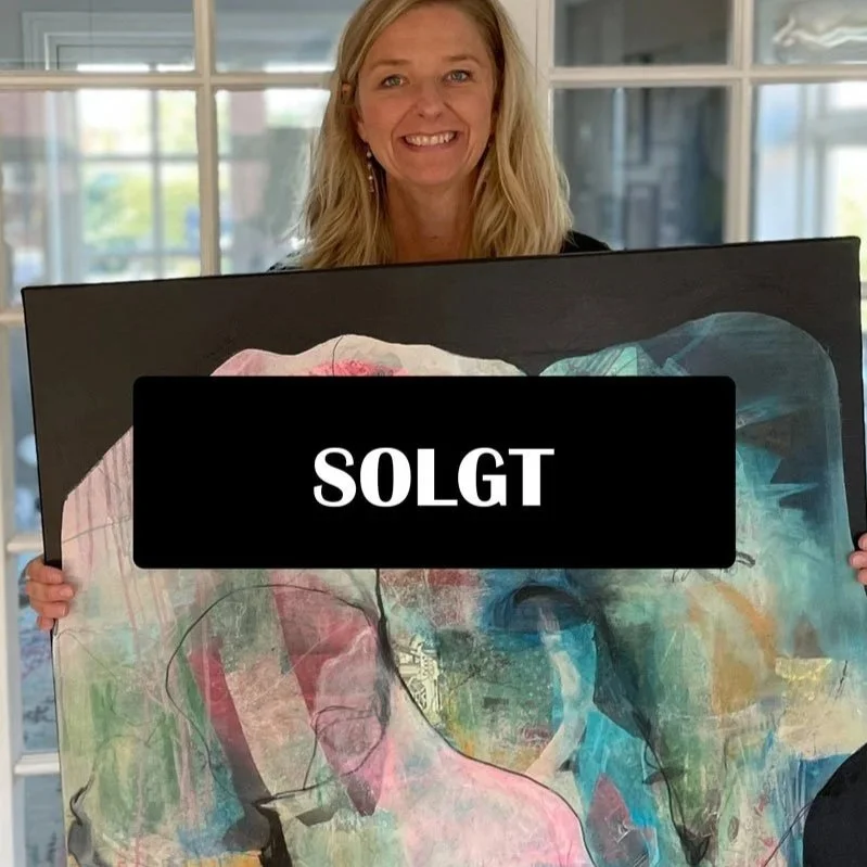 Billedkunstner Trine Studsgaard holder et farverigt kunstværk i abstrakt stil.