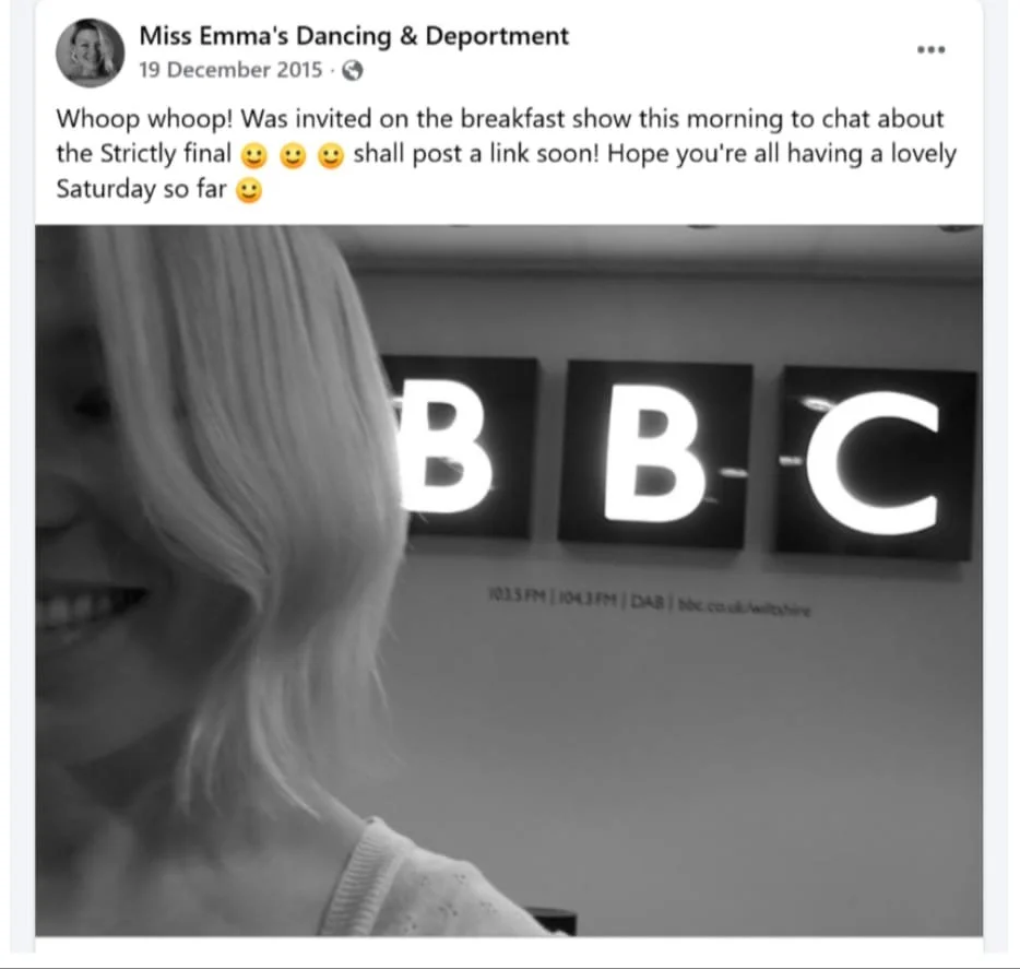 Black and white photo of a woman with blonde hair smiling, partially visible on the left, in front of three illuminated BBC signs on a wall.