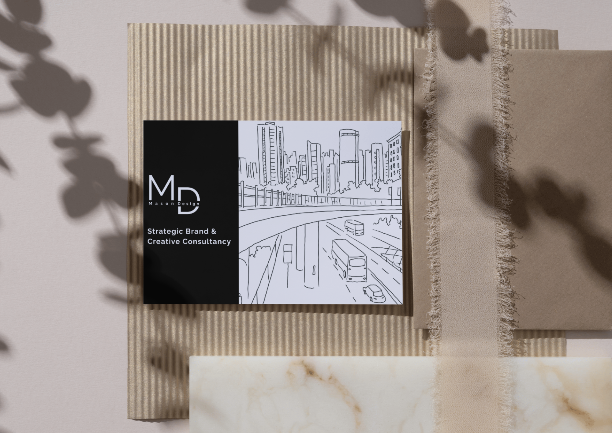Business card for Mason Design, a strategic brand and creative consultancy, placed on a textured beige surface with shadows of leaves, accompanied by a beige ribbon and a marble slab.