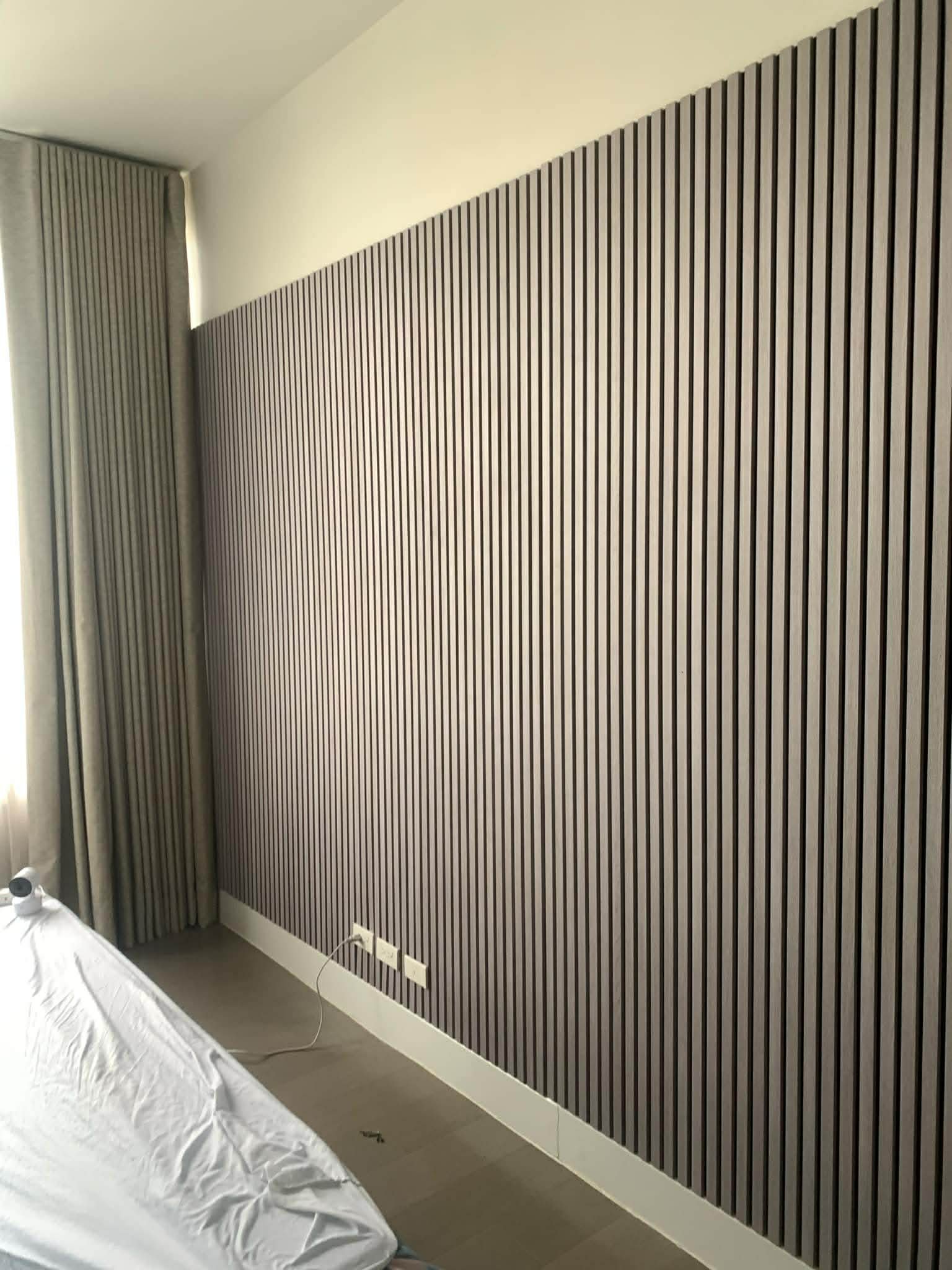 Interior wall with black and white vertical striped wallpaper and an electrical outlet with plugged-in cords.