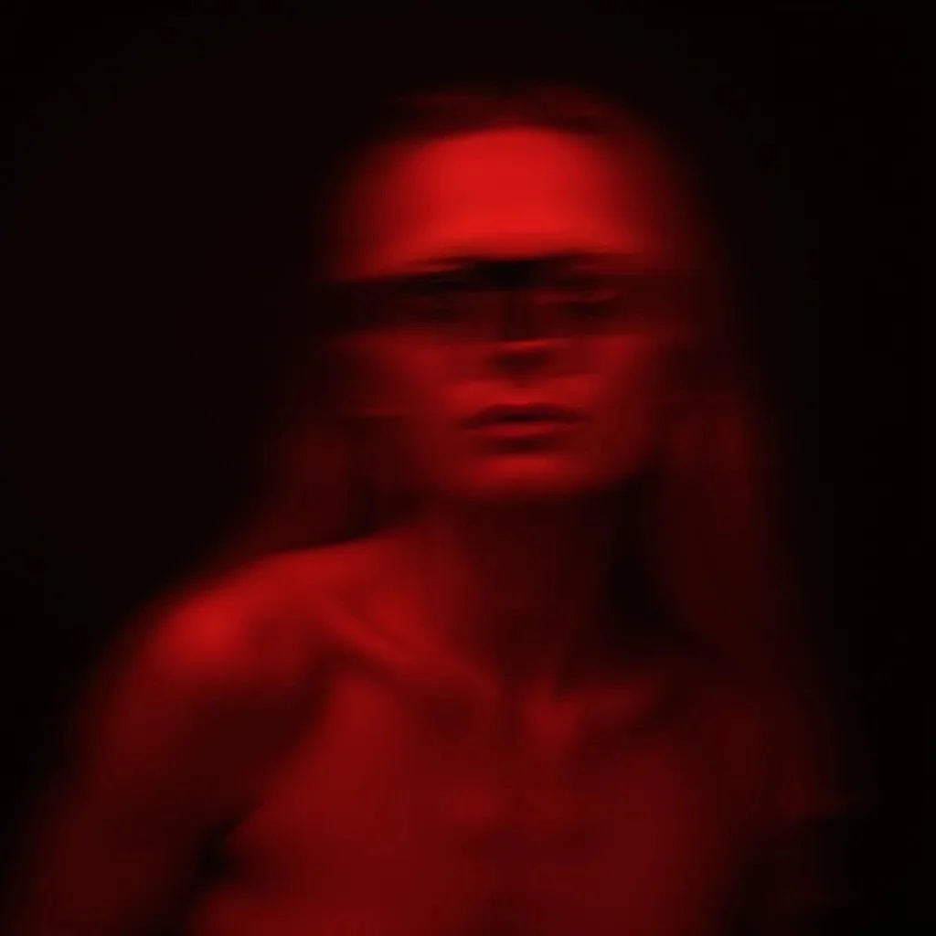 Blurred portrait of a Goddess ME. illuminated by red light in a dark background.
