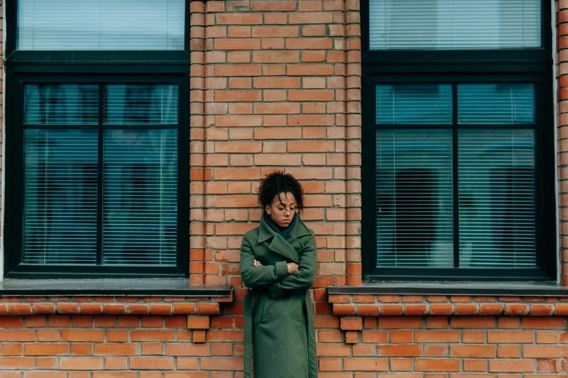 depressed african american woman leaning on brick wall