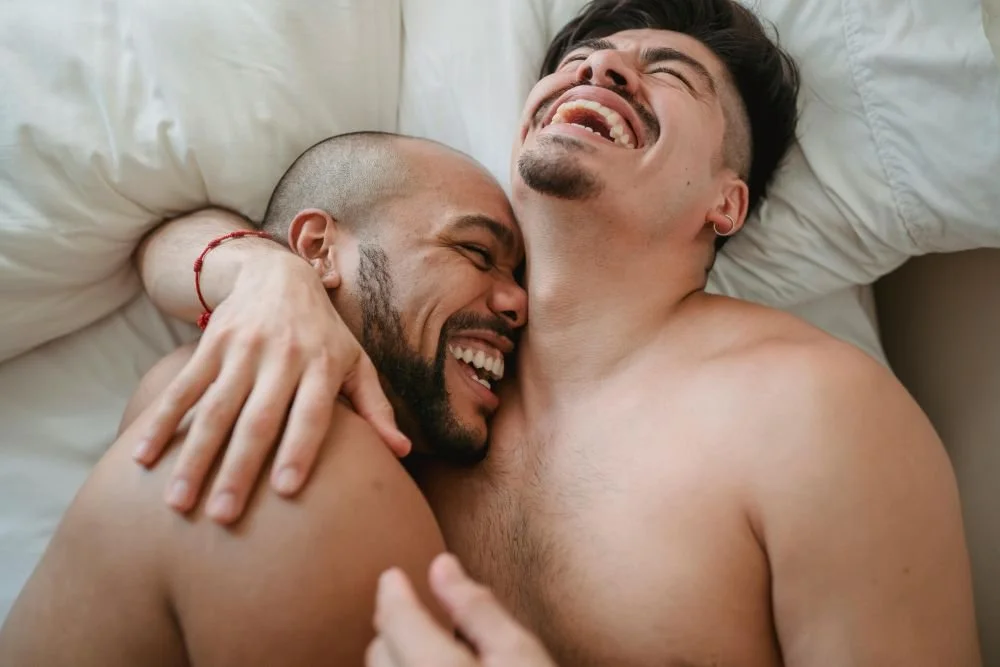 gay male couple in bed laughing