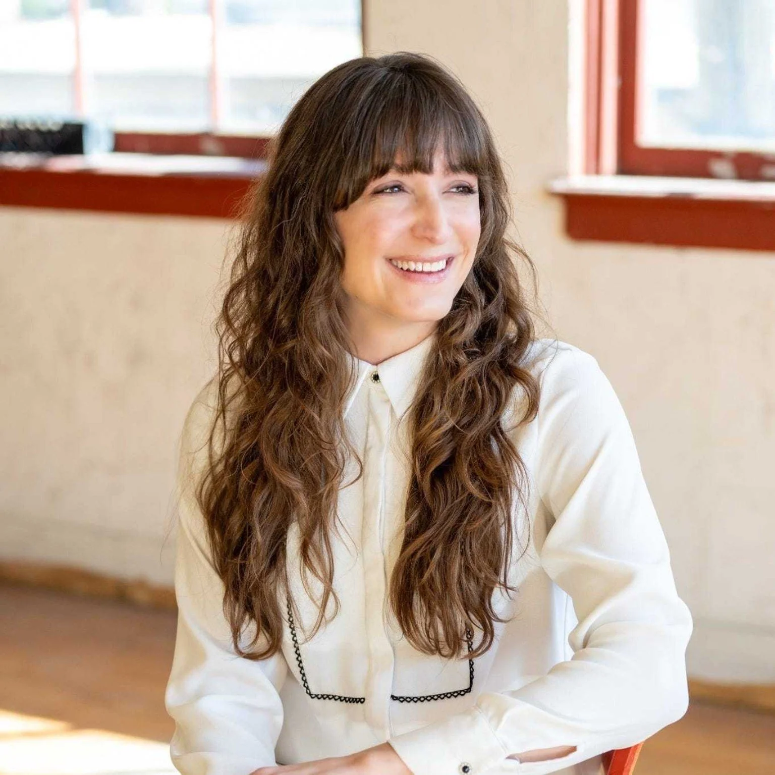 Hannah Greening, Founder and Principal of Rhize Urban Strategy, smiling in a sunlit room.