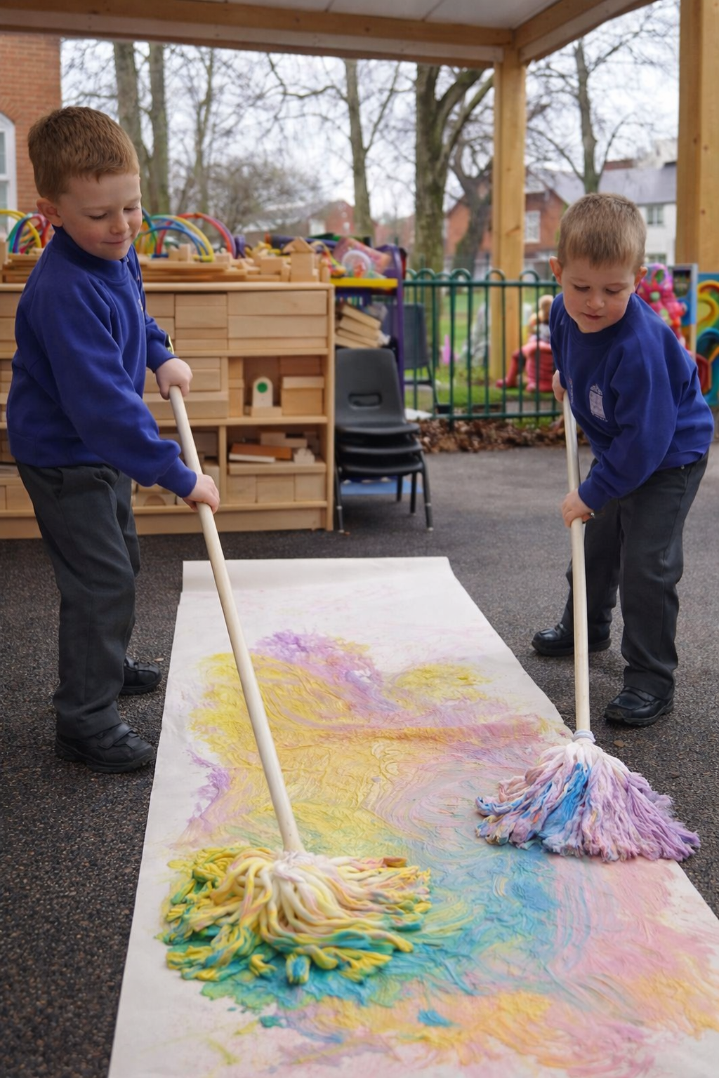 Kids pretending to mop a cafe floor using colorful paint.