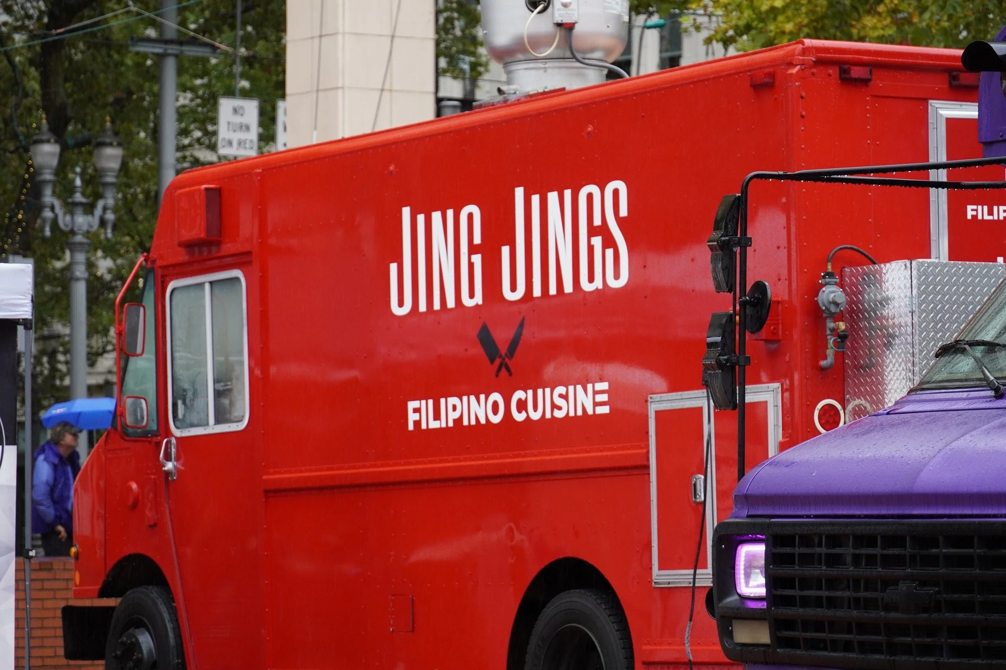 Red food truck with sign 'Jing Jings Filipino Cuisine' parked on street