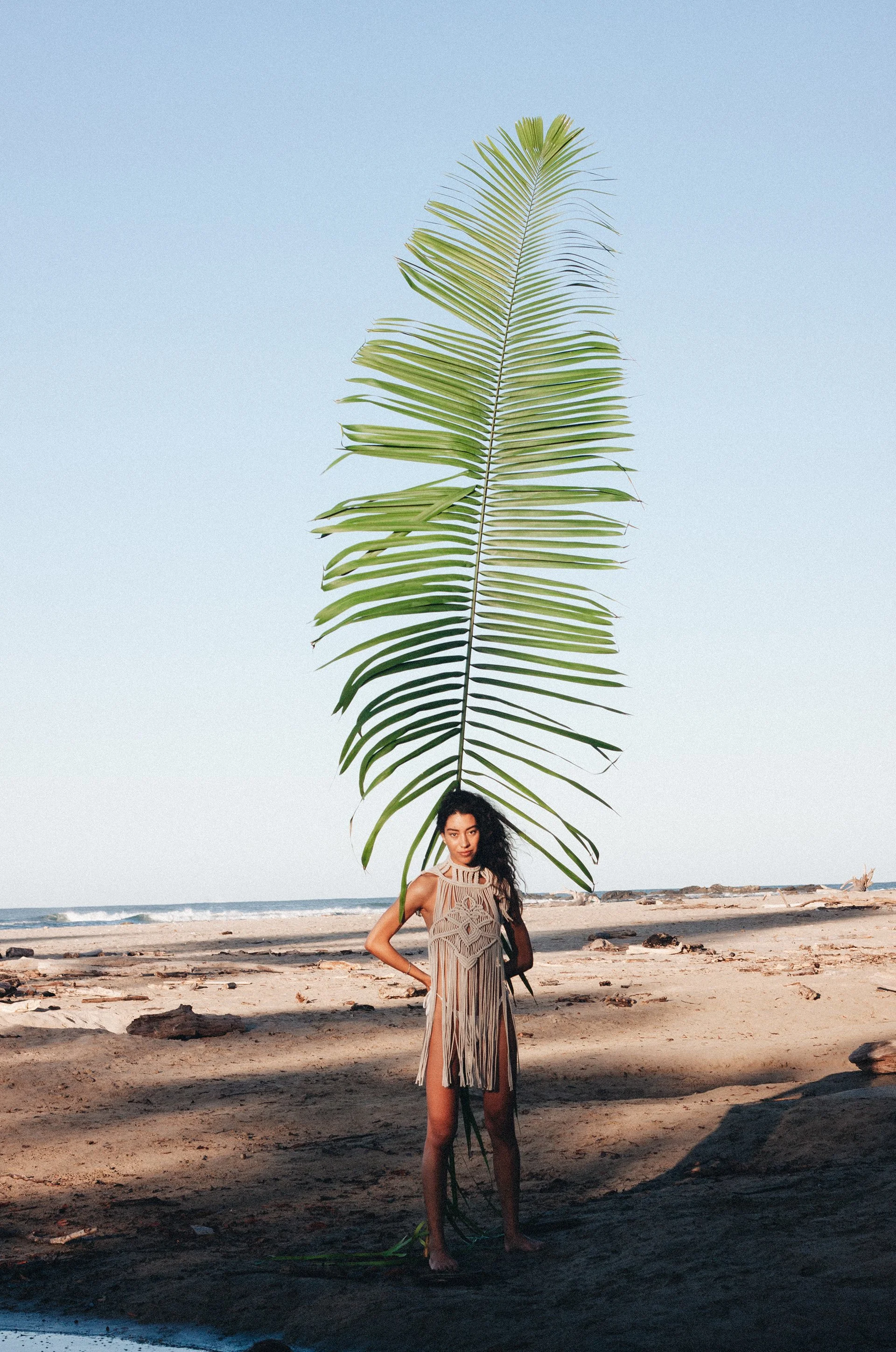 Photo of woman holding giant leaf on a beach for a designer brand