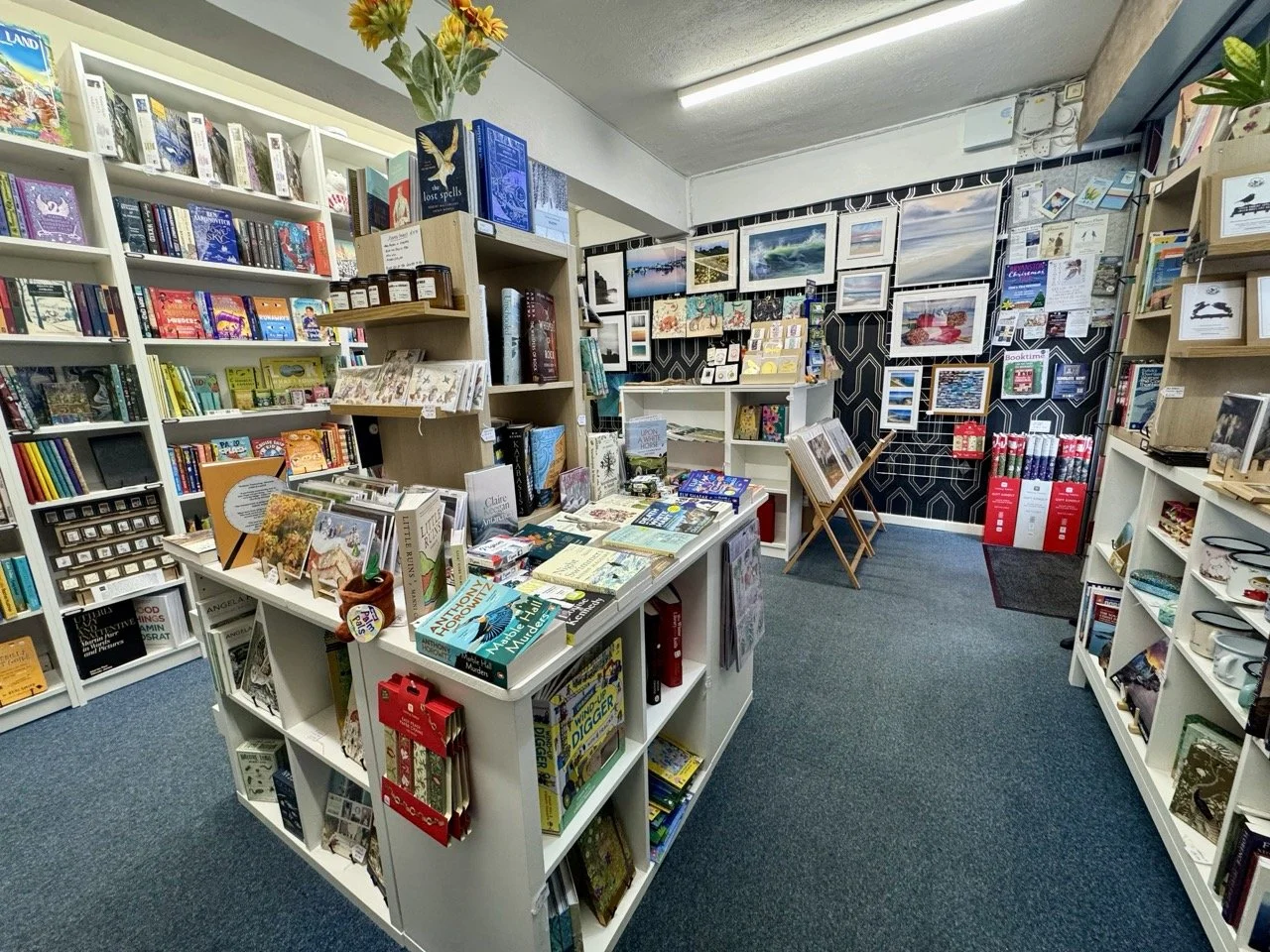 Inside a bookstore with shelves filled with books and artwork on the walls.