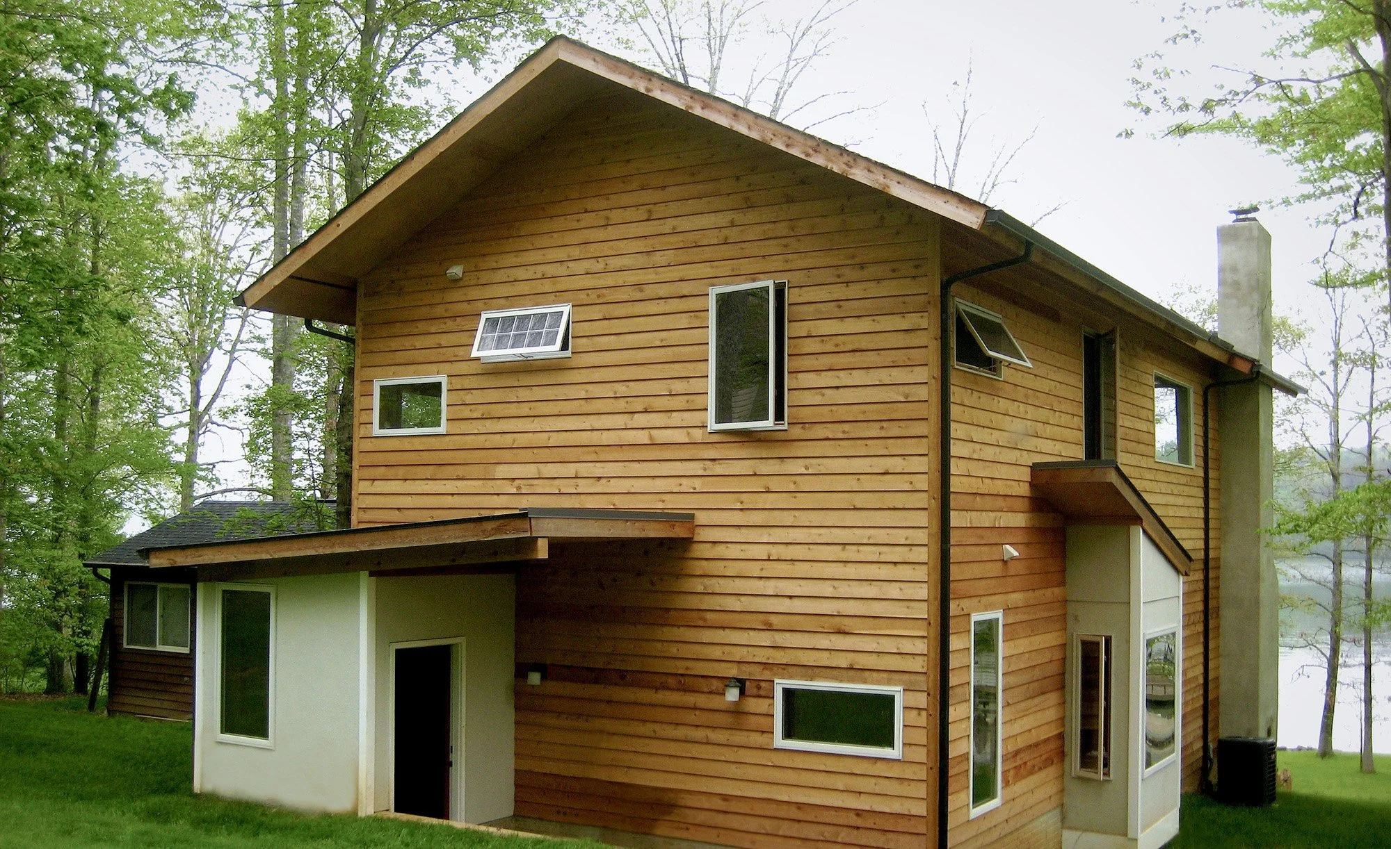 Cedar siding, carefully placed windows, and layered roof forms translate the logic of the forest canopy into architecture.