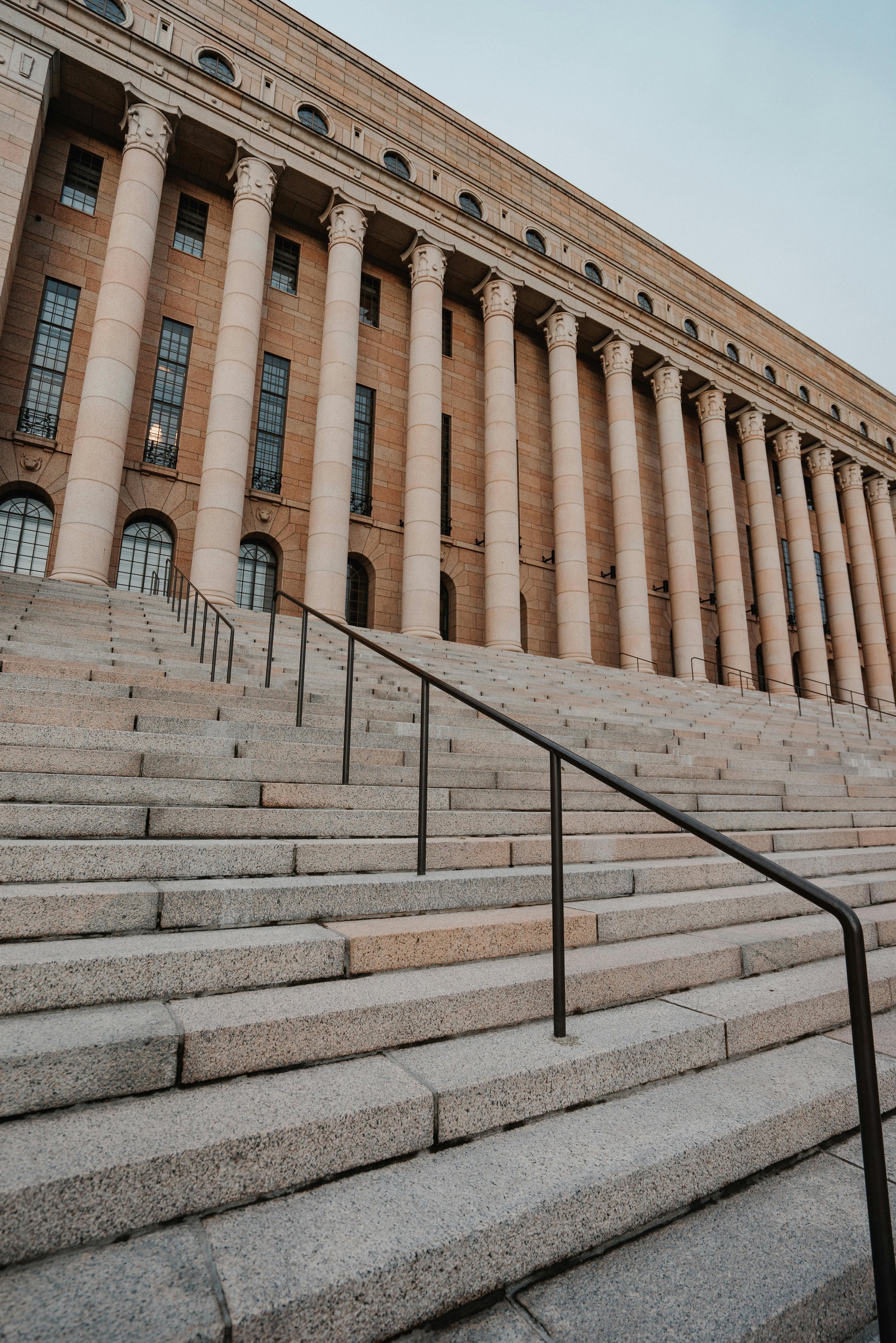 Stone steps leading to a large classical building with tall columns and arched windows.