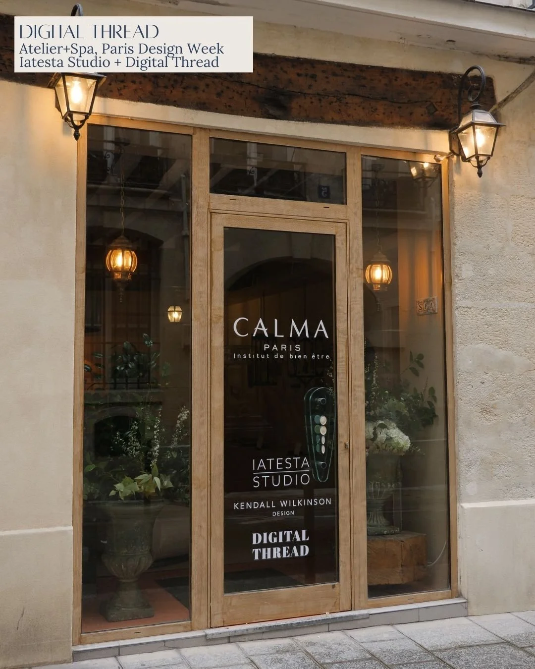 Storefront with glass door and windows, displaying signs for Calma Paris, Atelier+Spa Paris Design Week, and Digital Thread. Inside, there are potted plants and warm lighting.