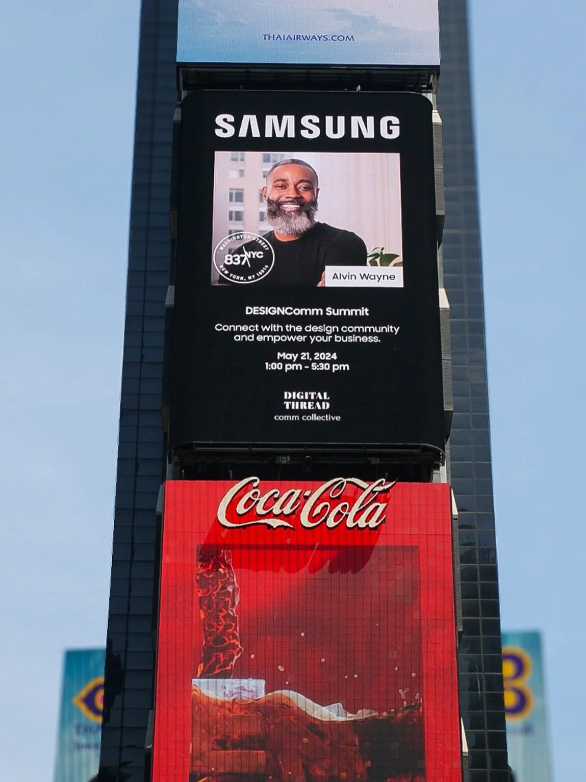 Digital billboard with an advertisement for the DESIGNComm Summit featuring a photo of Alvin Wayne, scheduled for May 21, 2024, from 1:00 pm to 5:30 pm. Below is a Coca-Cola advertisement with a close-up of a glass of cola.