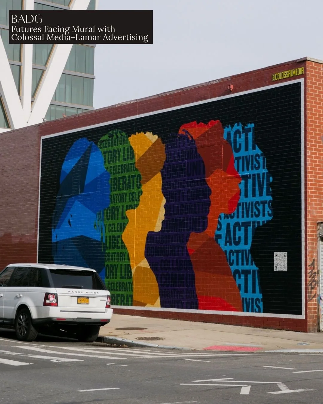 Colorful mural of four stylized human profiles in blue, green, yellow, purple, red, and orange facing each other on a brick wall. The profiles are filled with words like 'Celebrate,' 'Liberty,' 'Citizen,' 'Activist,' and 'Unite.'