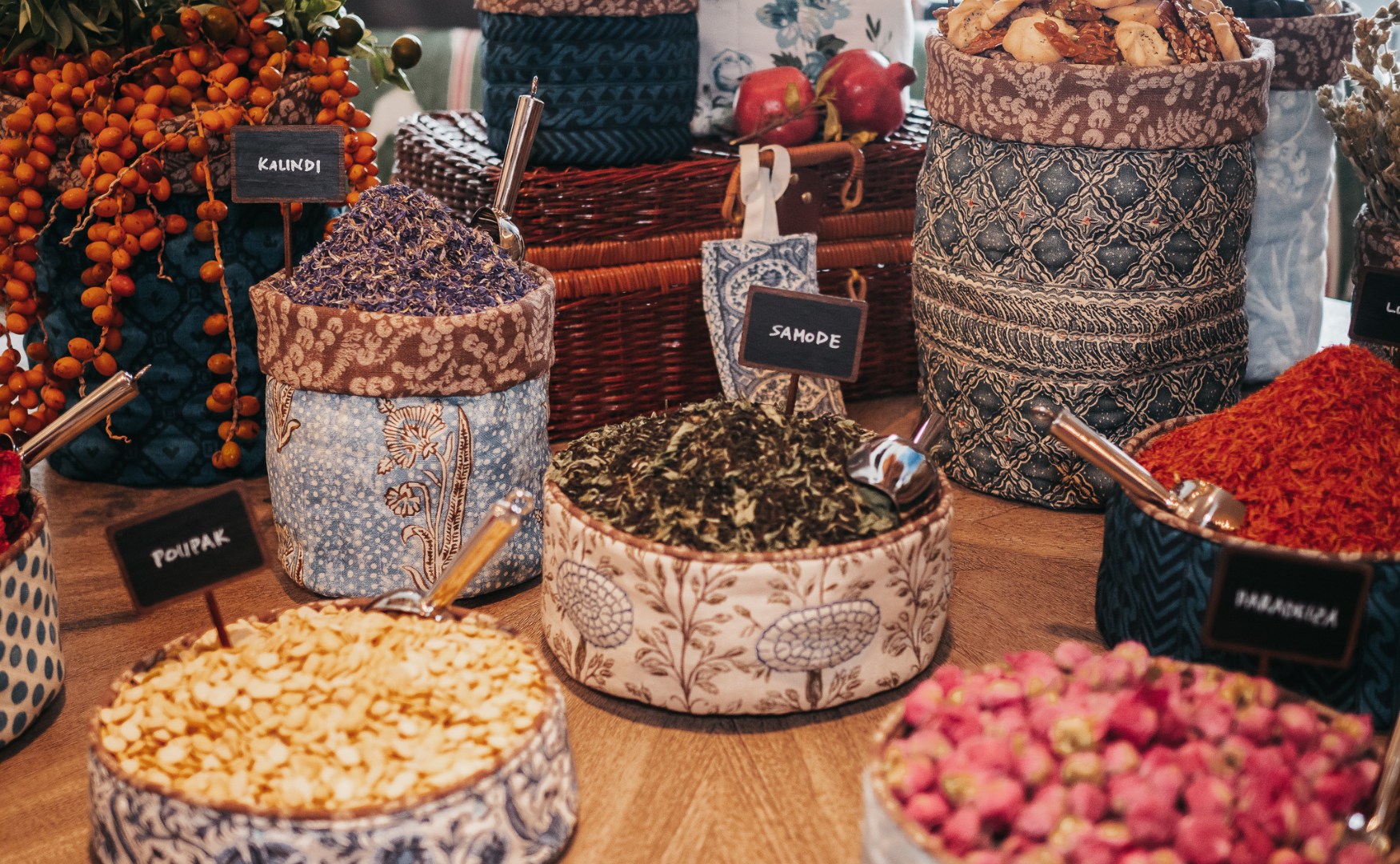 Assorted dried herbs and spices in fabric-lined jars at a spice market display.