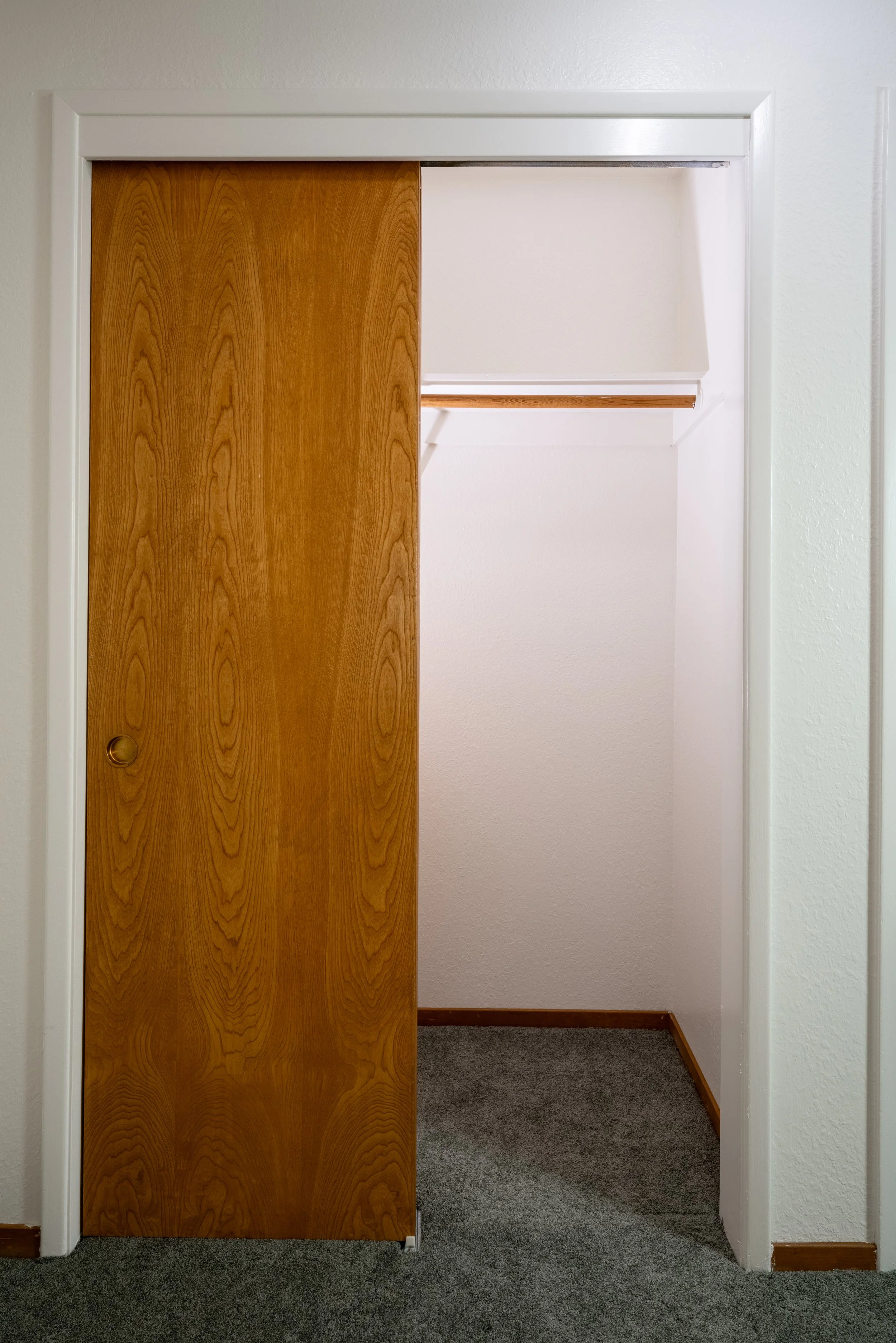 Apt. F: Canary Apartments in Calistoga, CA.   Empty closet with a wooden sliding door, white walls, and a gray carpeted floor.