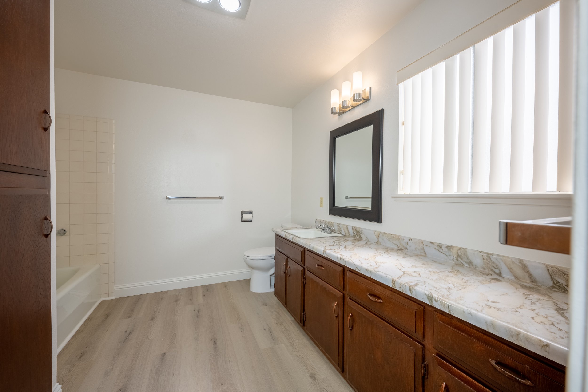 Apt. F Canary Apartments in Calistoga, CA.  Empty bathroom with a wooden vanity, marble countertop, mirror, shower, and toilet