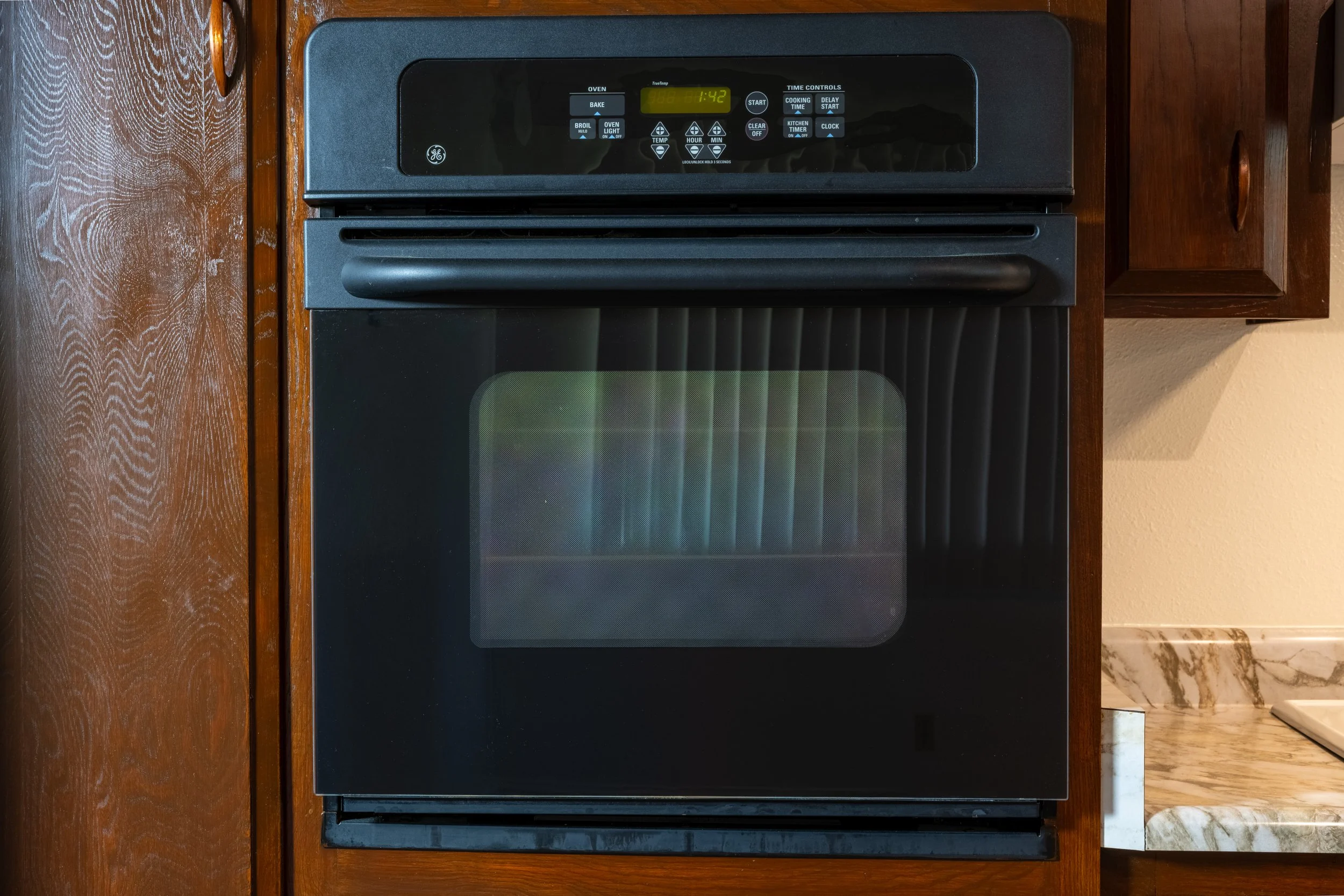 Apt. F: Canary Apartments in Calistoga, CA.   Black oven in wooden kitchen cabinetry, with a ceramic counter to the right.