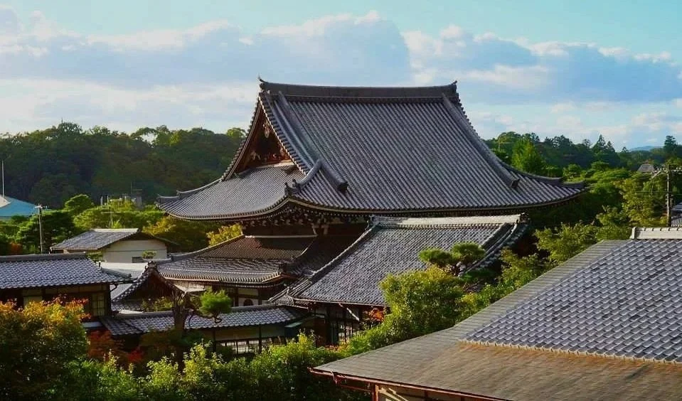 Historic Destination Hotel Marketing Content photography. Traditional Japanese temple surrounded by lush green trees with a blue sky and clouds in the background.