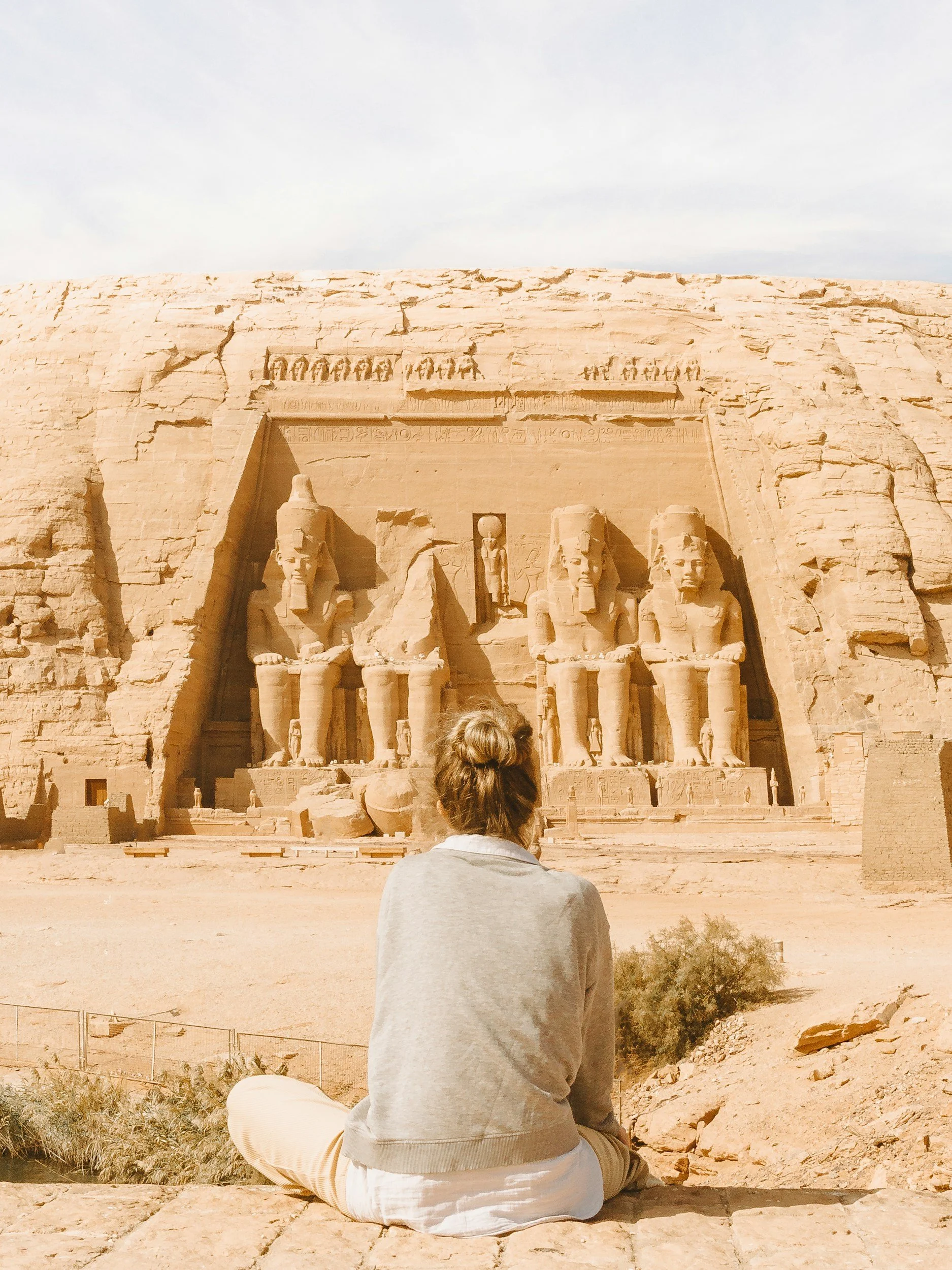 A woman dressed as an explorer standing in front of the Great Pyramid of Giza and the Sphinx in Egypt.