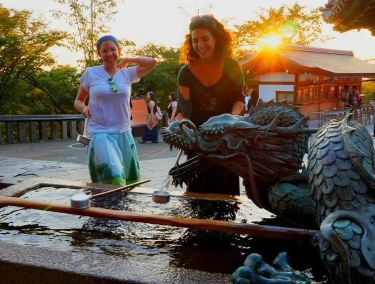 People in traditional costumes participating in a cultural festival at a temple, with a dragon figure and a crowd in the background.