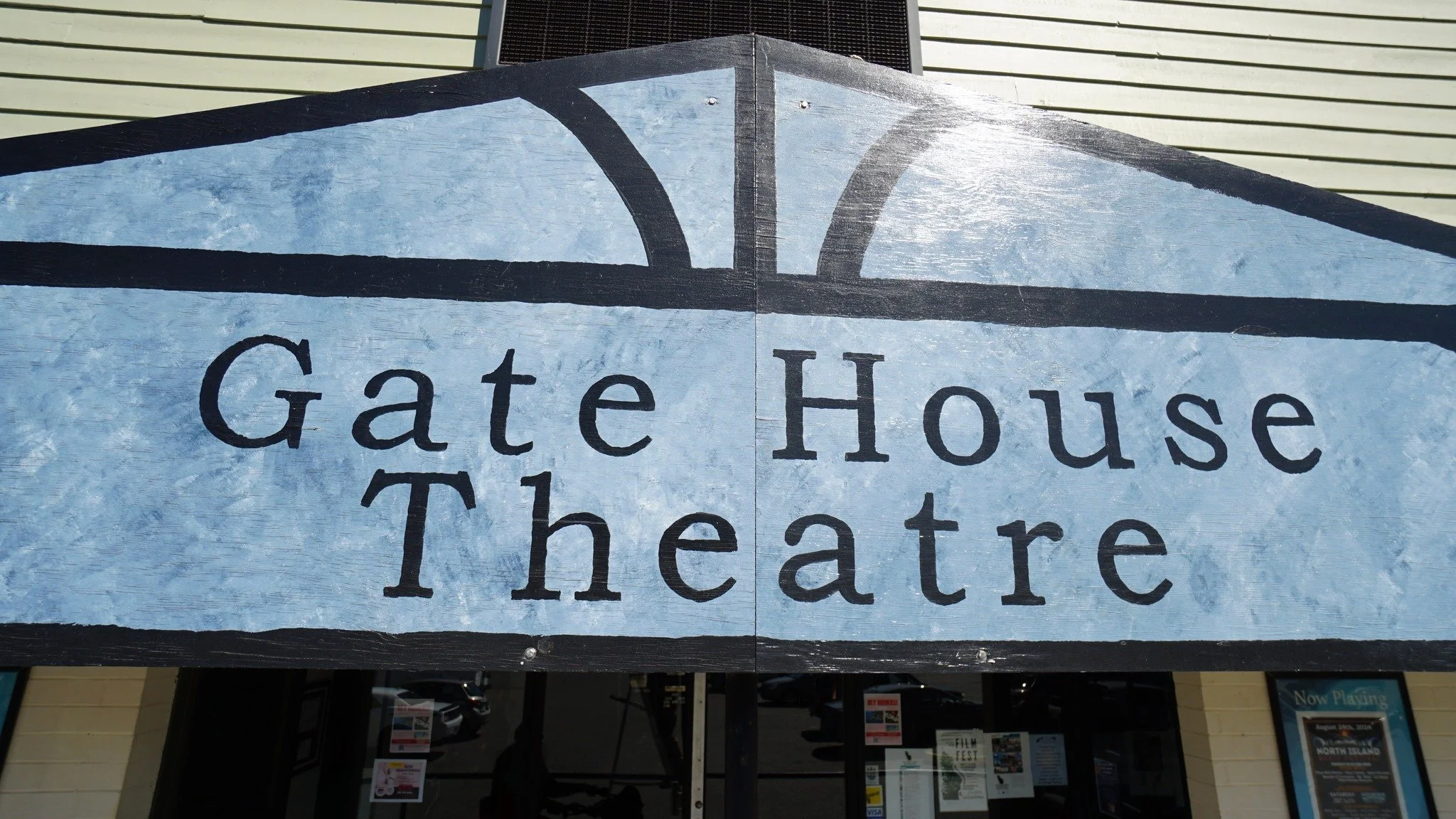 Sign for Gate House Theatre showing black text on a light blue background with decorative black border elements.