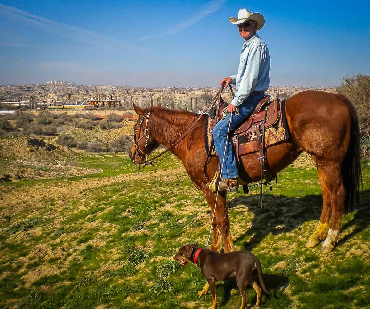 John Harrer riding his horse on a trail near Bakersfield with their dog alongside.