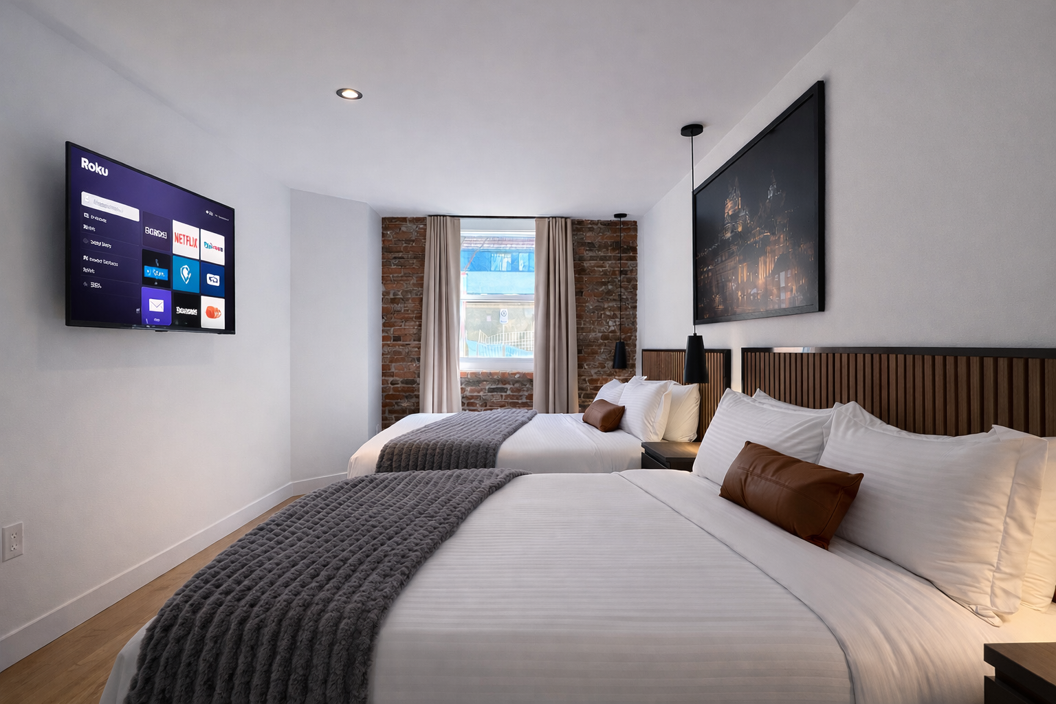 Chambre moderne avec deux lits, tête de lit en bois, télévision à écran plat, fenêtre avec rideaux, murs en briques, lampes suspendues, décoration minimaliste.