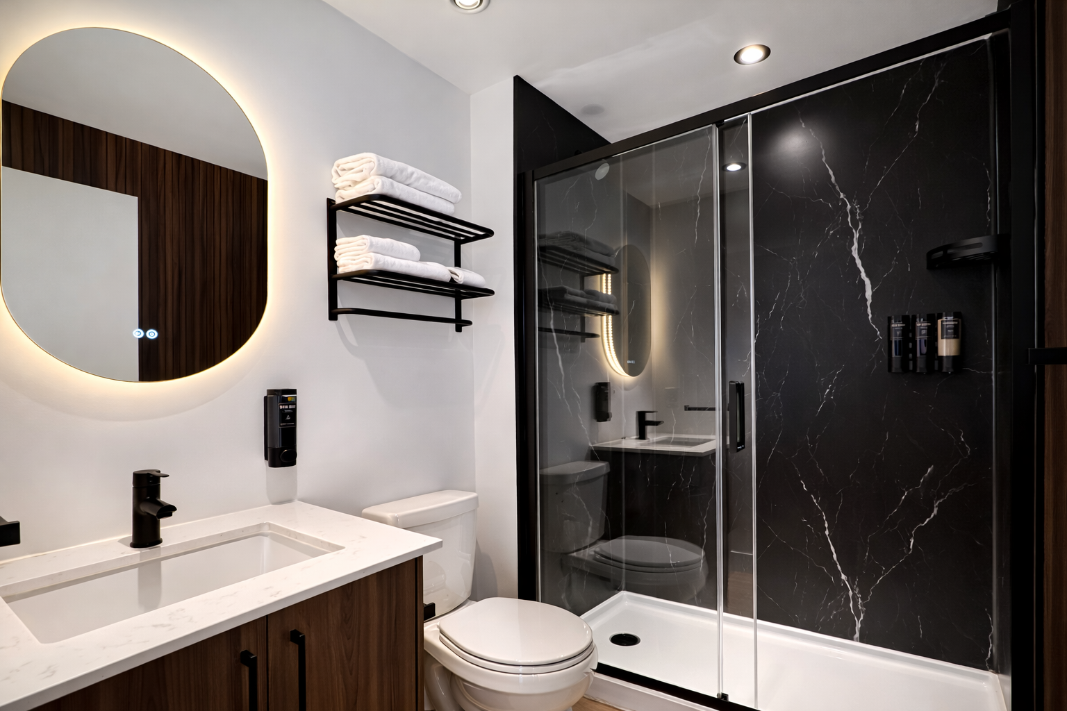 Salle de bain moderne avec un miroir rond à éclairage intégré, lavabo en marbre, étagères noirs avec serviettes blanches, toilette blanche, douche à l'italienne avec porte en verre et murs en marbre noir