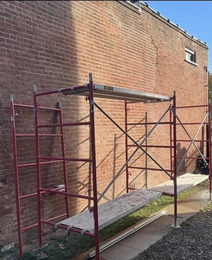 A modern house on a grassy hillside with snow-capped mountains in the background under a cloudy sky.