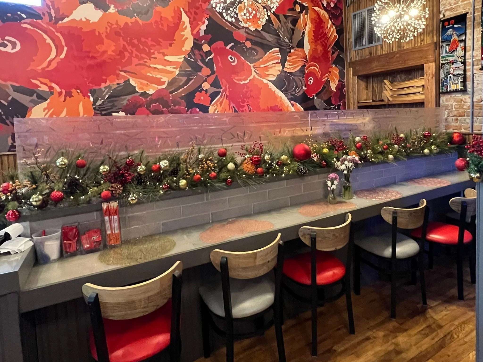 Decorated dining area with a bar counter, festive Christmas decorations, vases with flowers, and colorful mural of fish and floral design on the wall.