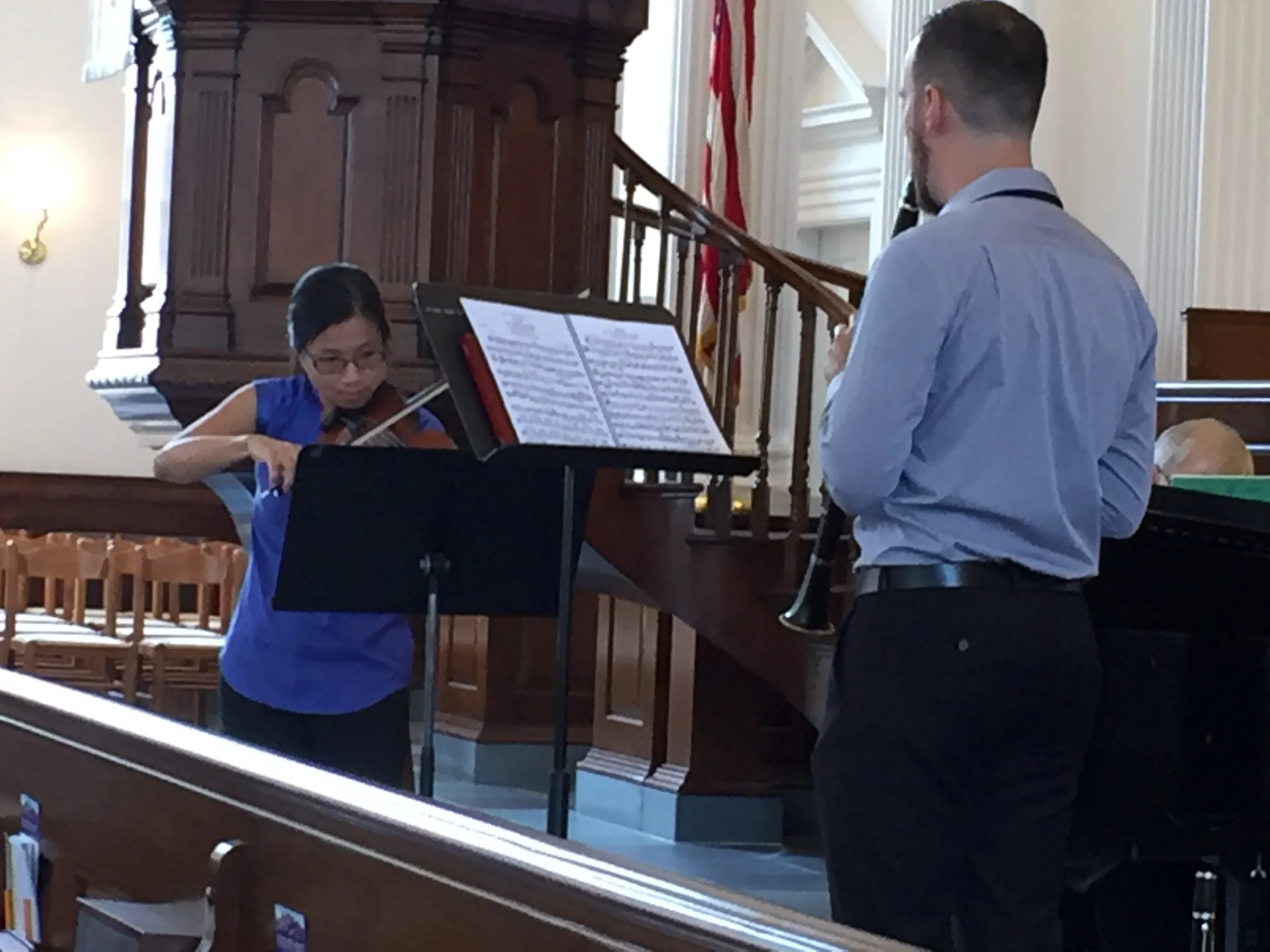 Richmond Chamber Players. A young girl playing the violin with a man playing the clarinet in a church or concert hall.