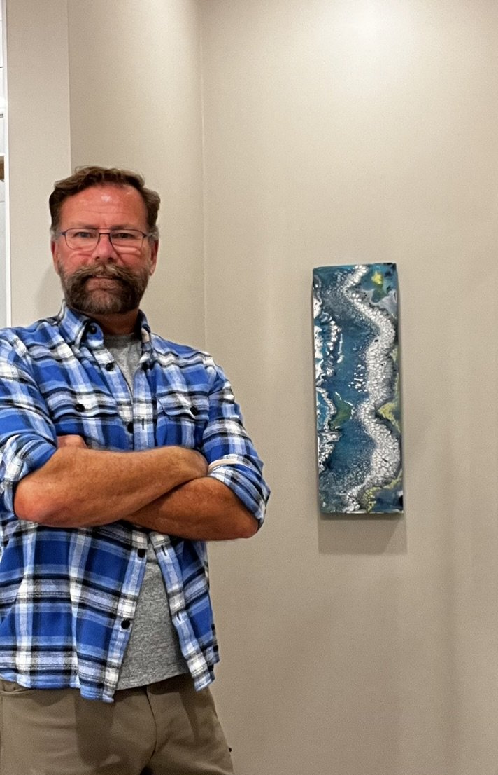 Collector beside a narrow blue and white abstract painting installed on a wall