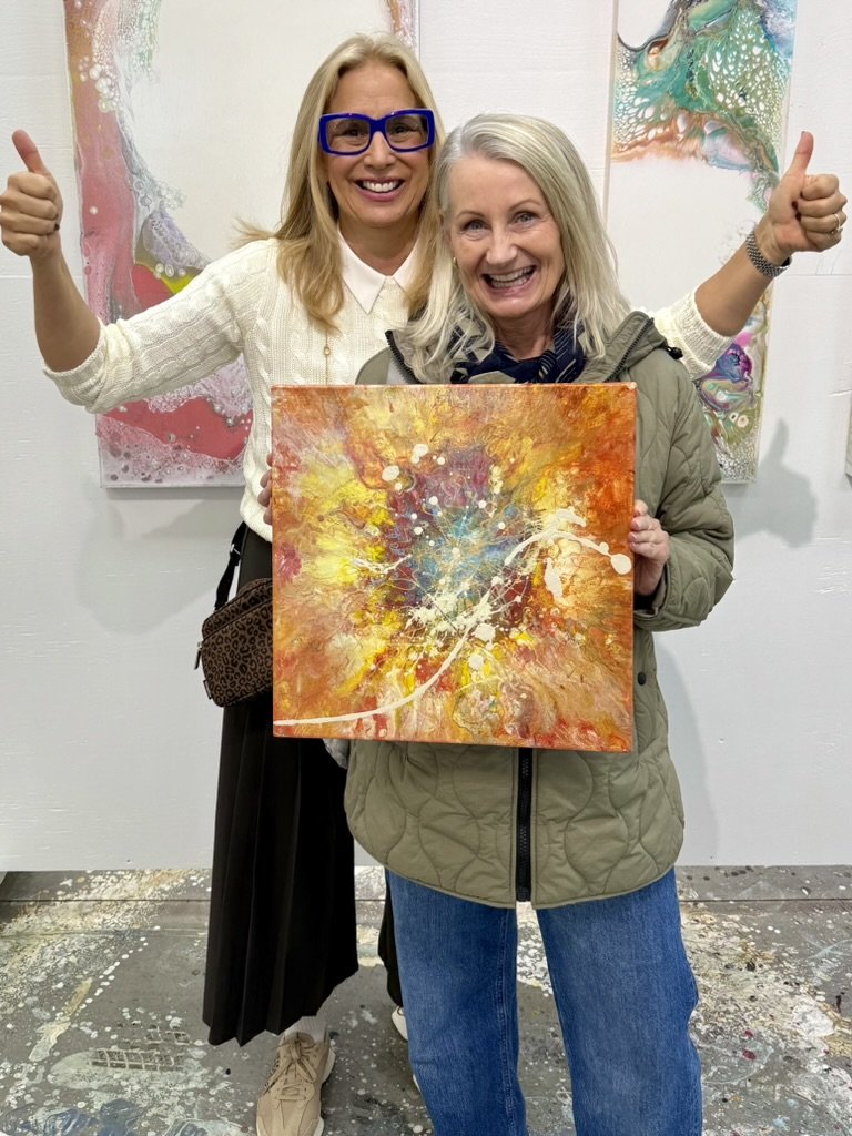 Cheryl Wheeler with a collector holding a vibrant orange abstract painting