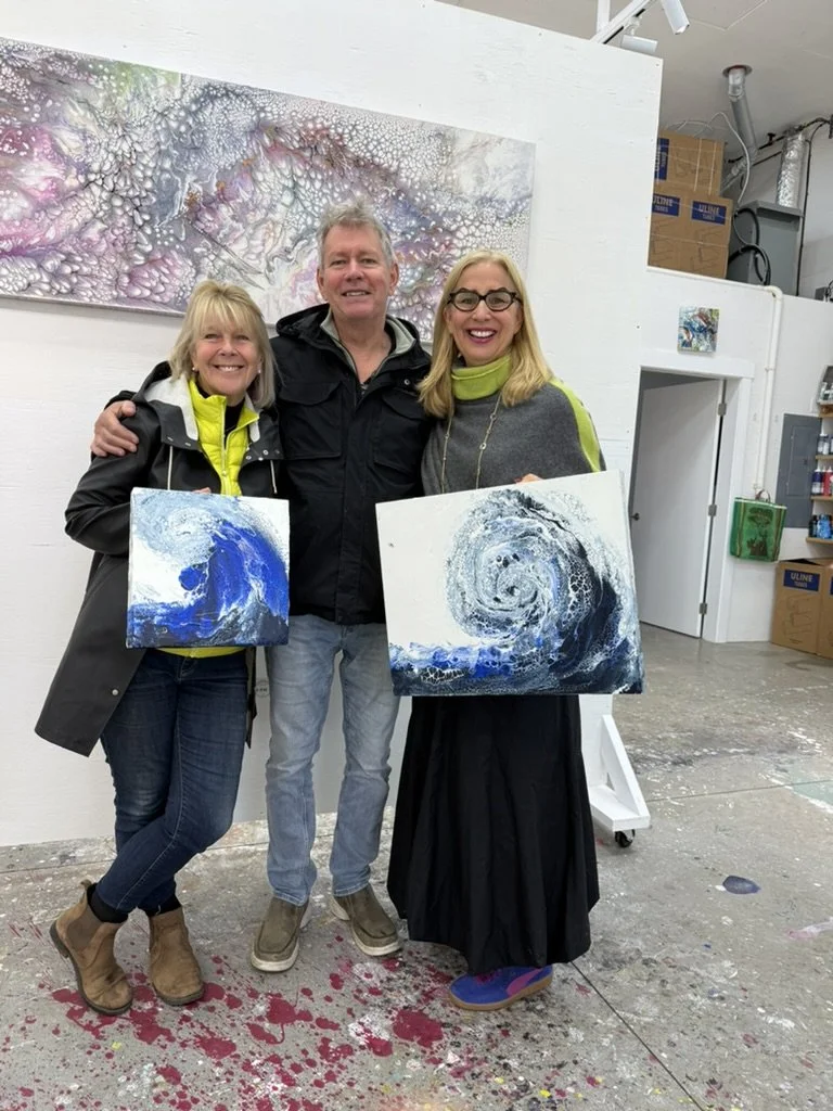 Cheryl Wheeler with two collectors holding blue wave paintings