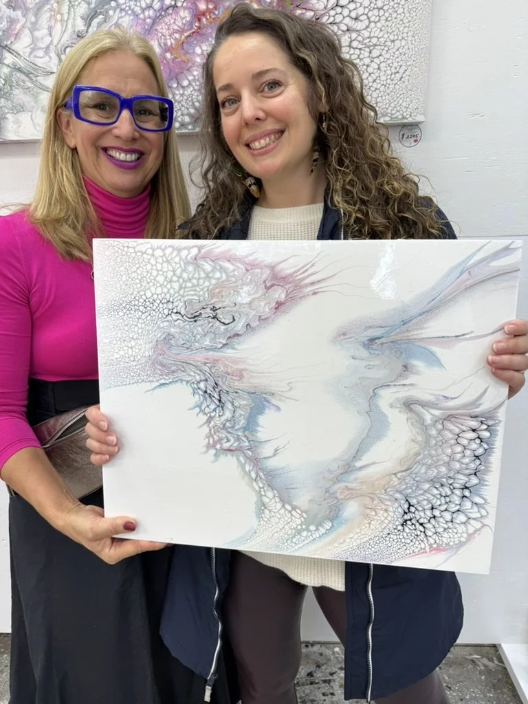 Cheryl Wheeler and a collector holding a pale blue and pink abstract painting