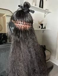 The image shows a person with long, straight black hair having their hair sectioned and pinned up, possibly for styling or hair treatment.