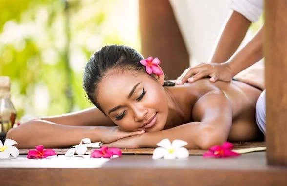 Woman receiving a massage at a spa with flower decorations.