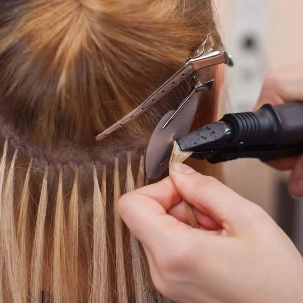 Someone is using a hot tool to straighten red hair, with hair clips holding sections of hair in place.