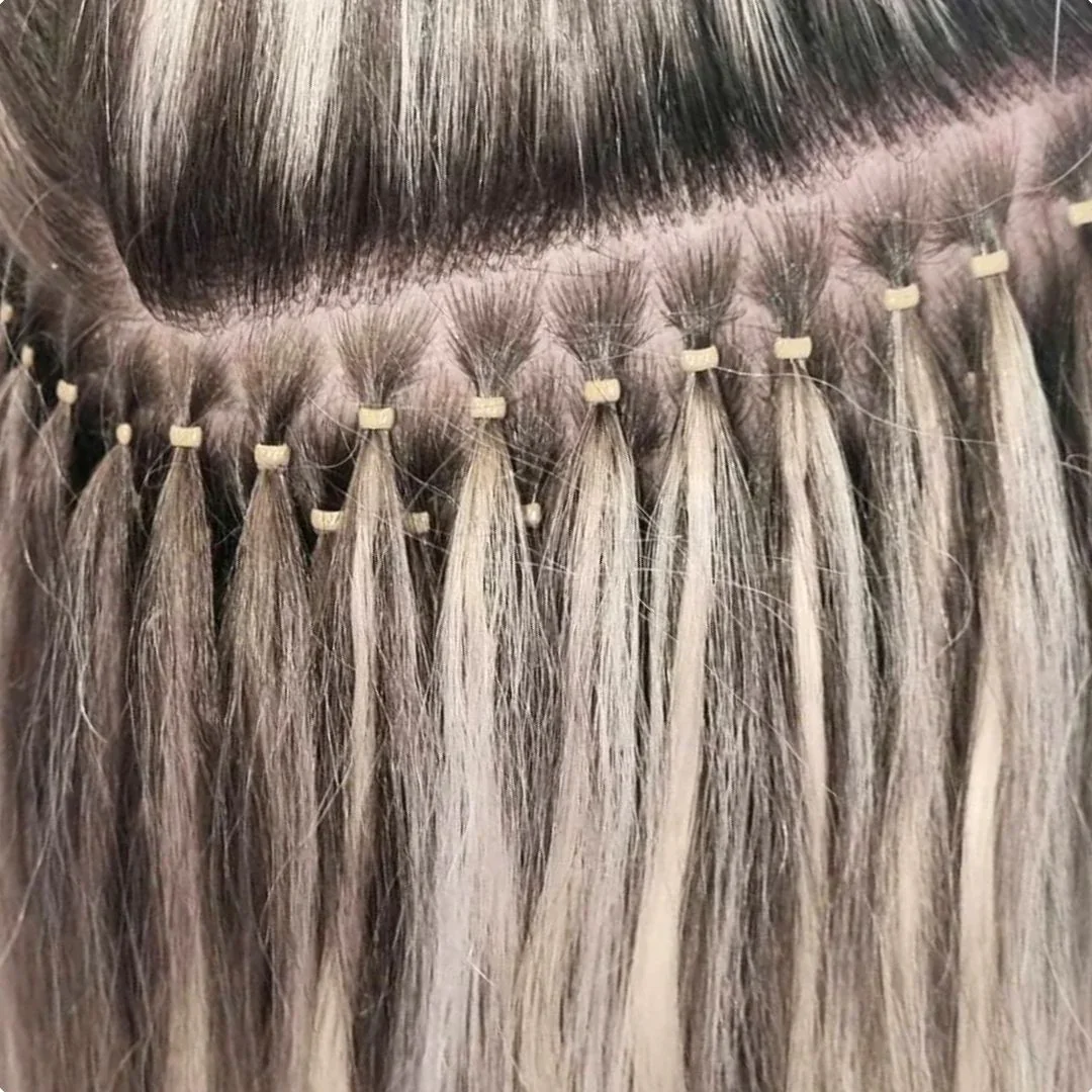 Close-up of a person's head showing hair extensions with small beige clips attaching blonde hair extensions to existing hair.