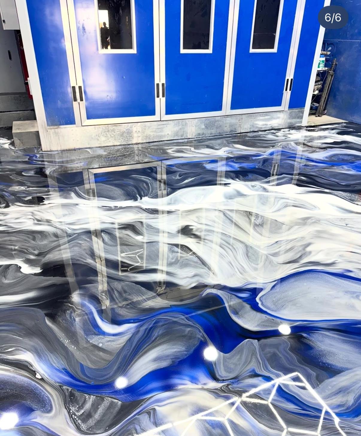 Reflection of blue storage cabinets on a highly polished, swirling marble-patterned floor.
