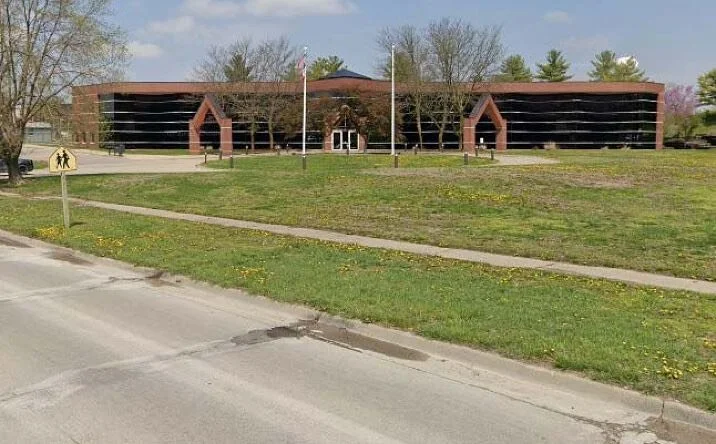 New Hope Healing Chariton office is housed in this Stone church with tall steeple, arched windows, and steps leading to entrance, parked cars in front.