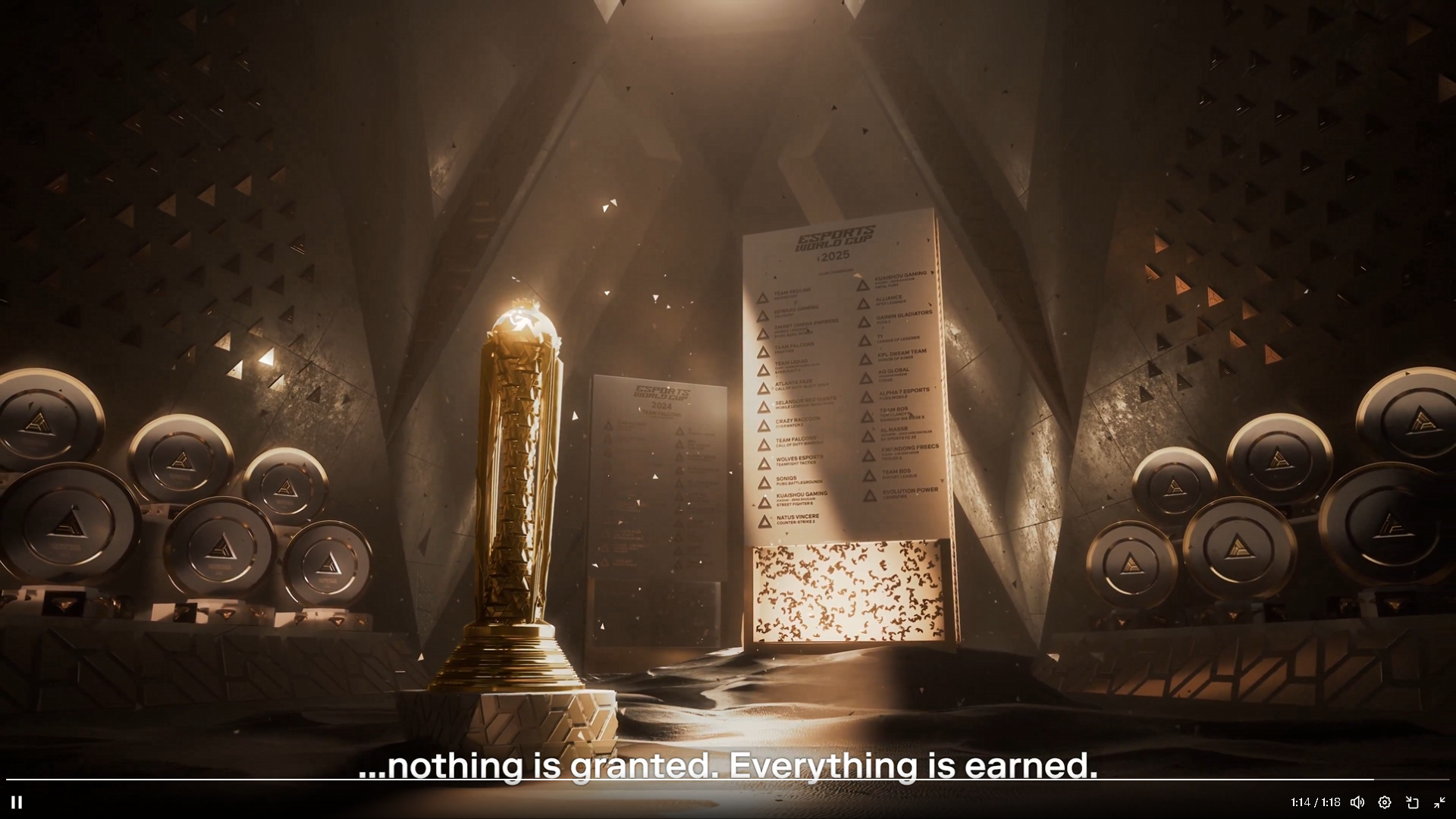 A golden trophy stands on a pedestal with a backdrop of large banners listing esports teams and a wall of speakers in a sleek, dark room, illuminated by focused lighting, with a subtitle reading 'nothing is granted. Everything is earned.'
