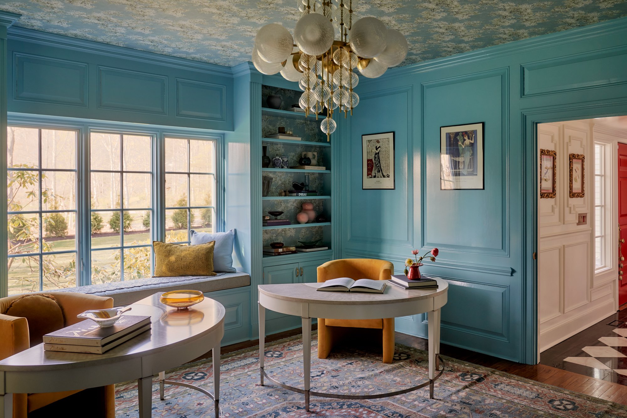 A saturated palette sets the tone in this creative retreat, where glossy cerulean millwork wraps the room in clarity and focus. Twin demi-lune desks invite both solo work and collaboration, while ochre velvet chairs and a hand-knotted rug layer in wa