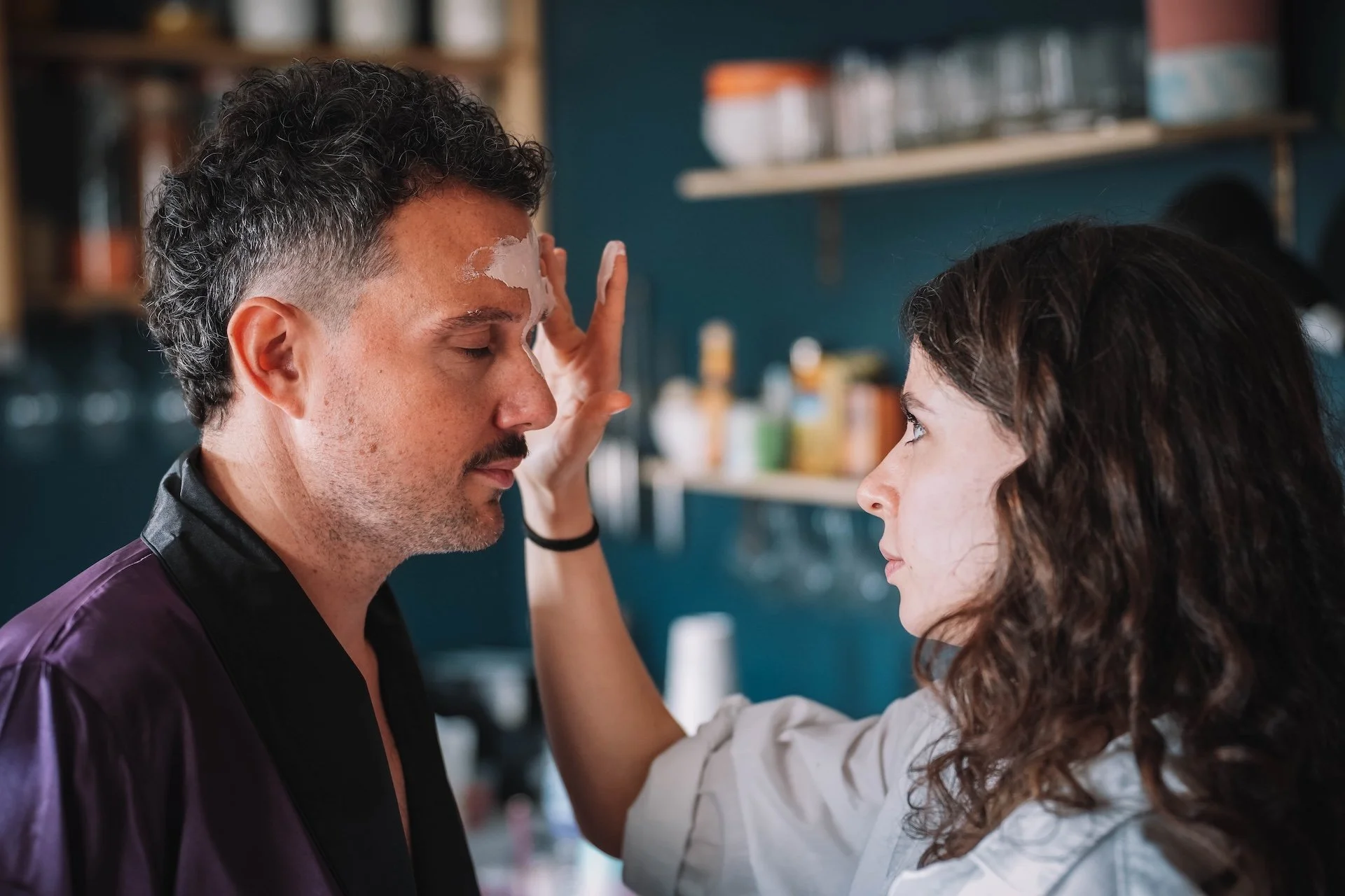 A woman applying facial cream to a man at a beauty or skincare salon.